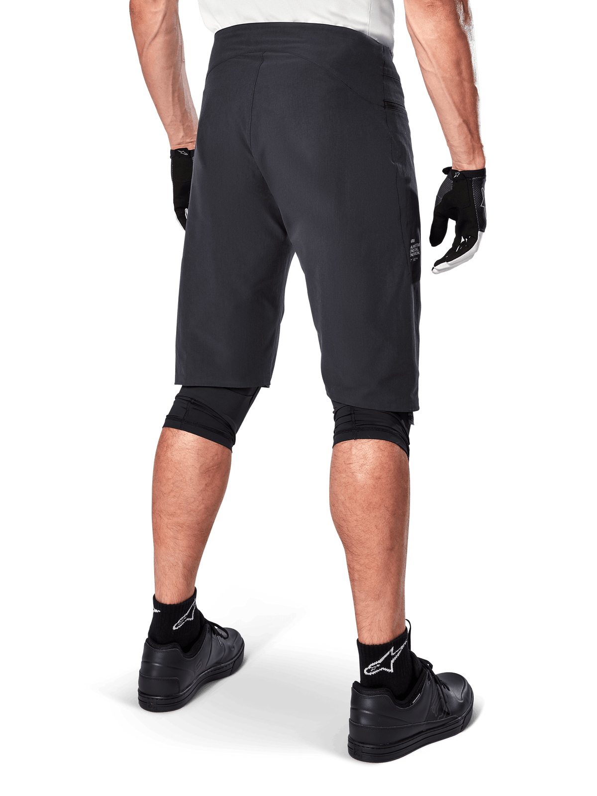 Short Alpinestars A-Aria, short de VTT, noir, vue arrière montrant la coupe performance et le design épuré, porté avec des gants noirs et des chaussettes arborant le logo blanc Astars, équipement de cyclisme technique pour le tout-terrain
