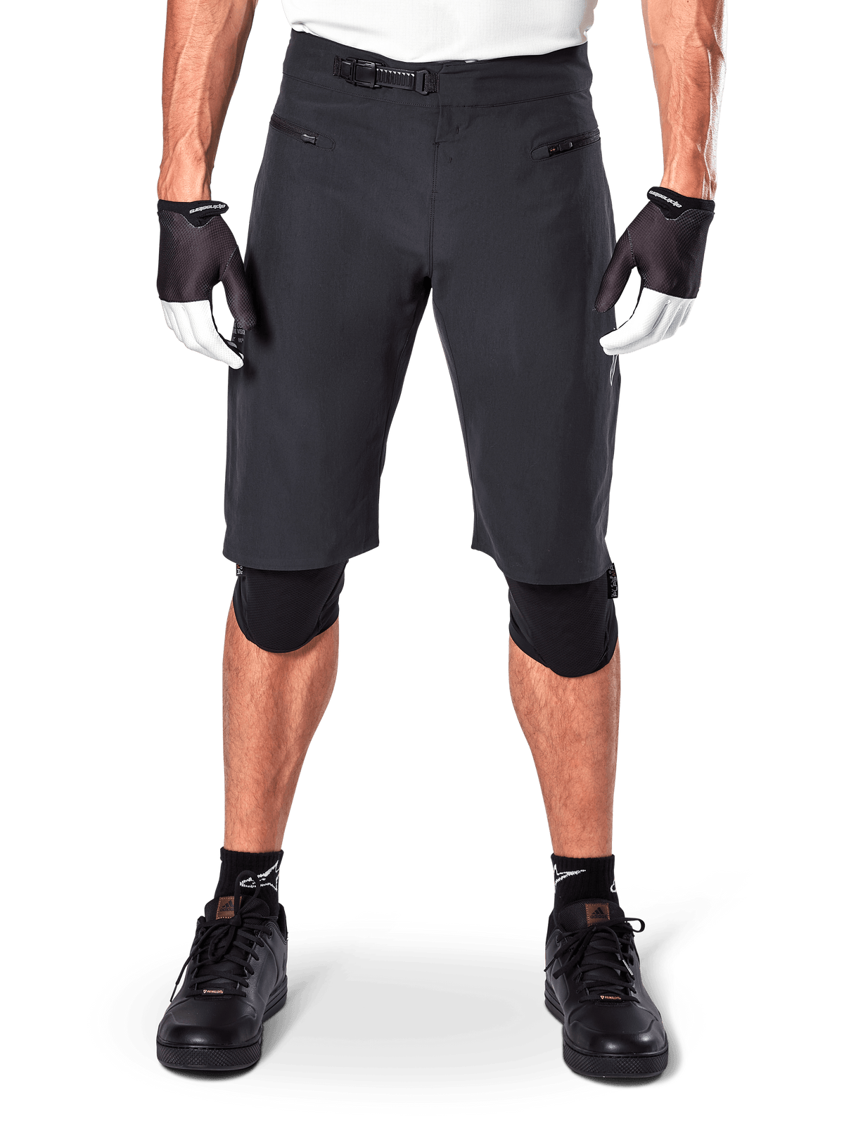 Short Alpinestars A-Aria, short de VTT noir, doté d'une fermeture à rochet à la taille et de poches zippées, porté avec des gants noirs et blancs et des genouillères, équipement technique de cyclisme pour le tout-terrain