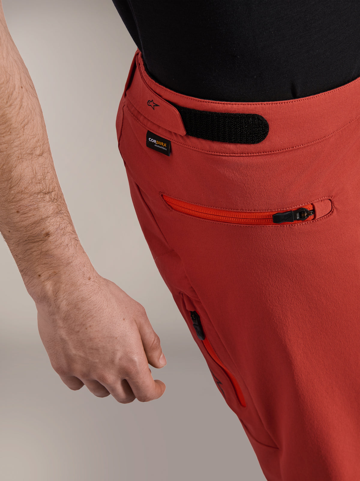 Short Alpinestars A-Dura Elite, Orange Foncé, gros plan du profil latéral présentant l'ajusteur de taille à crochet et boucle, le logo Cordura® et une poche latérale zippée, short de VTT haut de gamme.