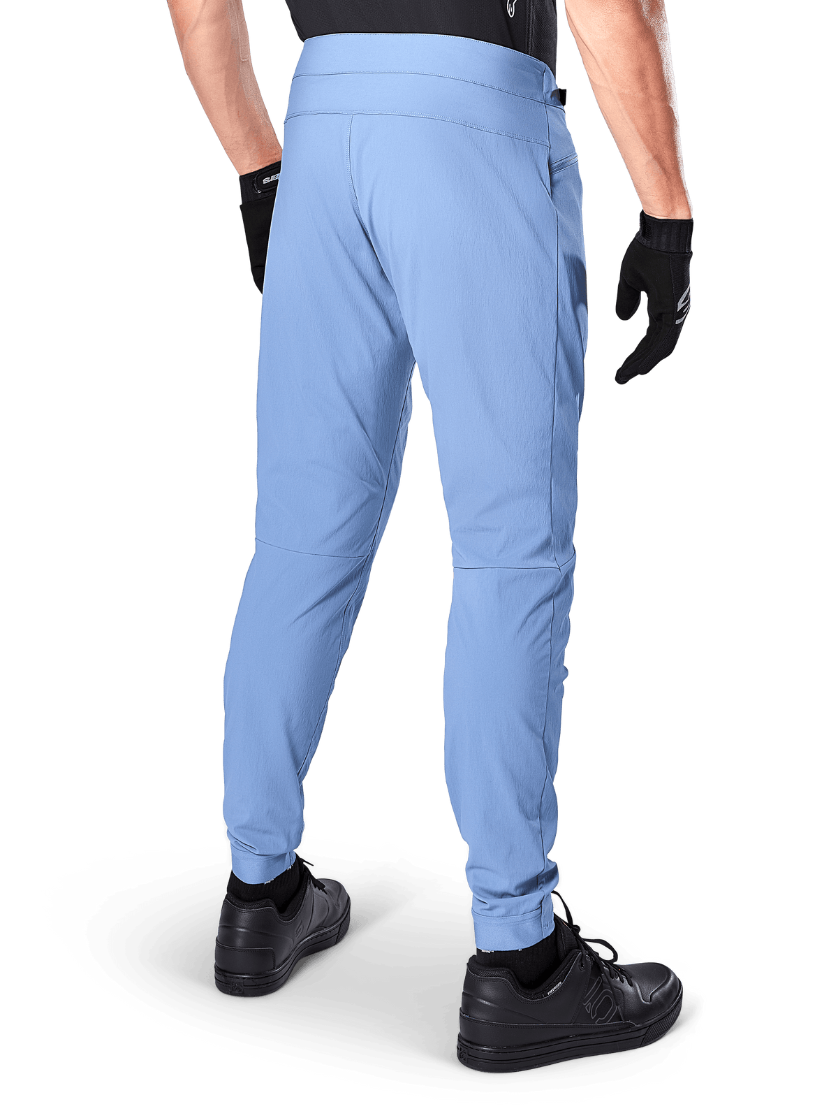 Pantalon Alpinestars A-Dura, pantalon de VTT, Bleu Infinity, vue arrière montrant la coupe régulière et les chevilles élastiquées, porté avec des gants noirs et des chaussures noires, vêtement de cyclisme durable en tissu extensible 2 voies.
