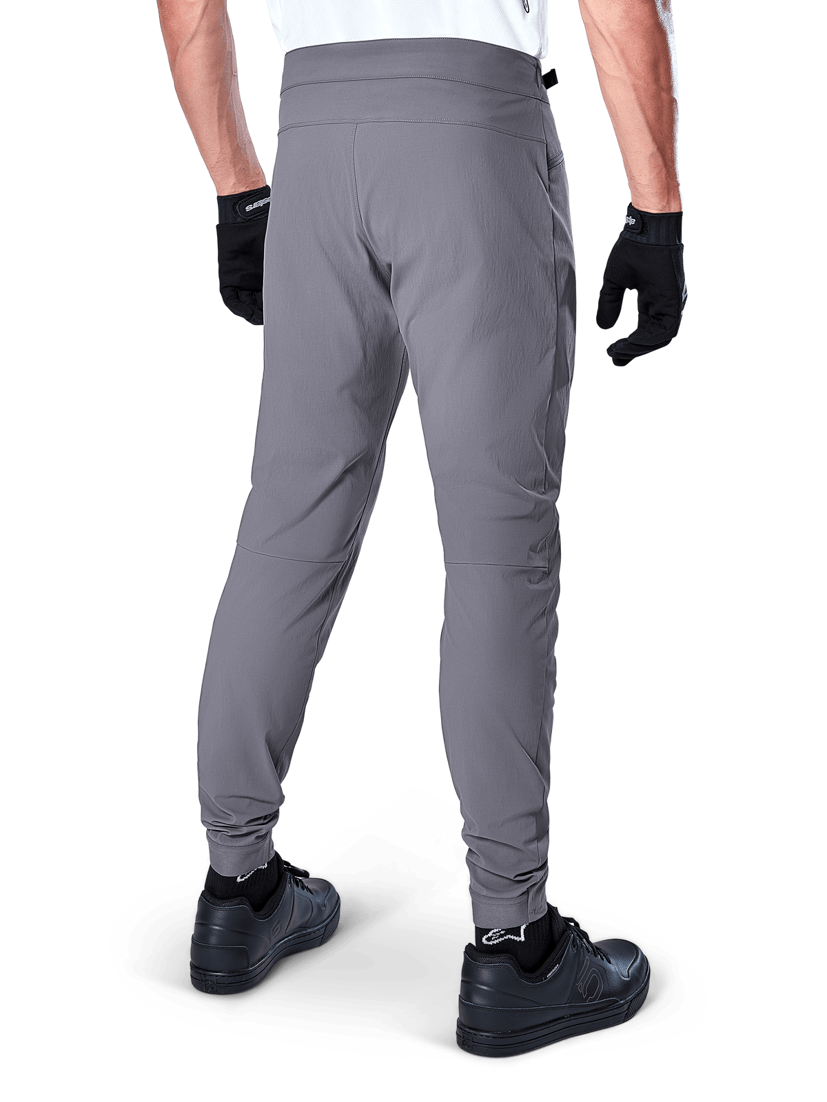 Pantalon Alpinestars A-Dura, pantalon de VTT, gris foncé, vue arrière du modèle portant l'équipement, doté d'un tissu extensible 2 directions et de bas de jambe élastiqués, coordonné avec des gants noirs et des baskets pour un look prêt pour le cyclisme