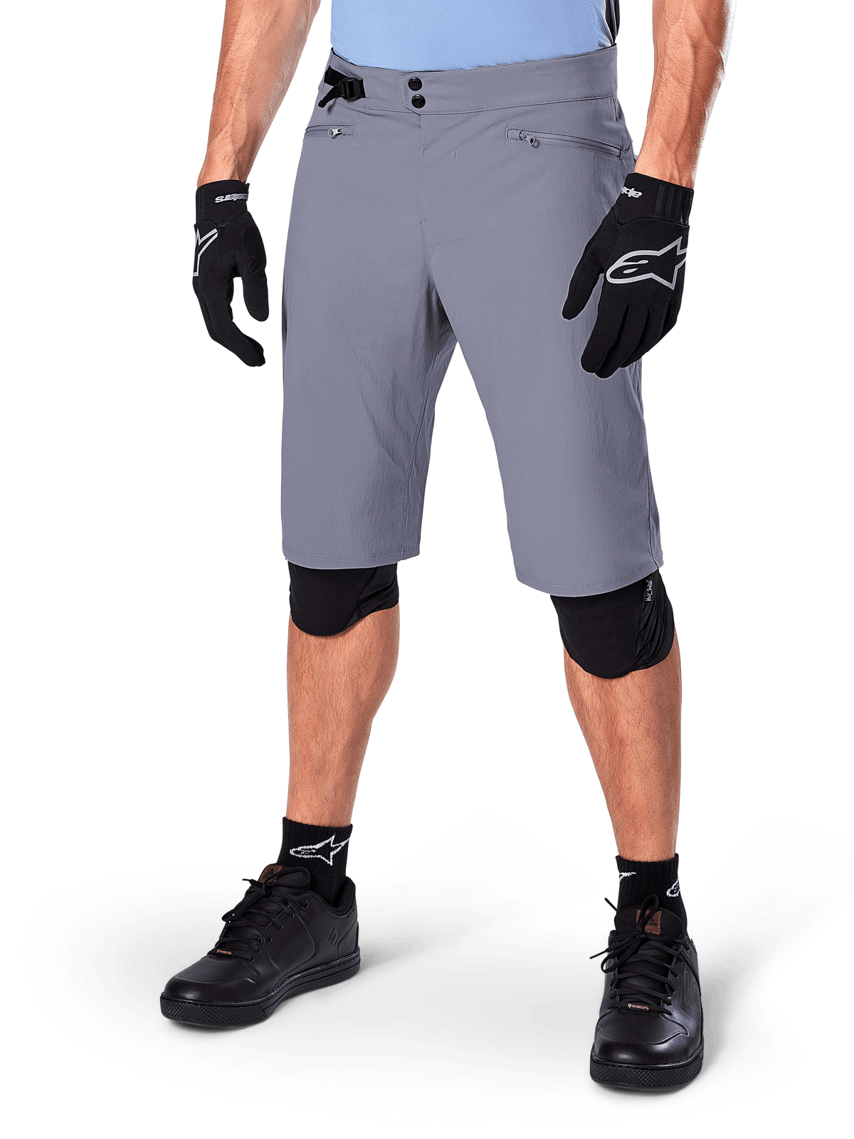 Alpinestars A-Dura Shorts, Dark Gray Mountain Bike Shorts, paired with black gloves and knee guards, featuring zippered pockets and double snap closure, rugged cycling gear for off-road trails