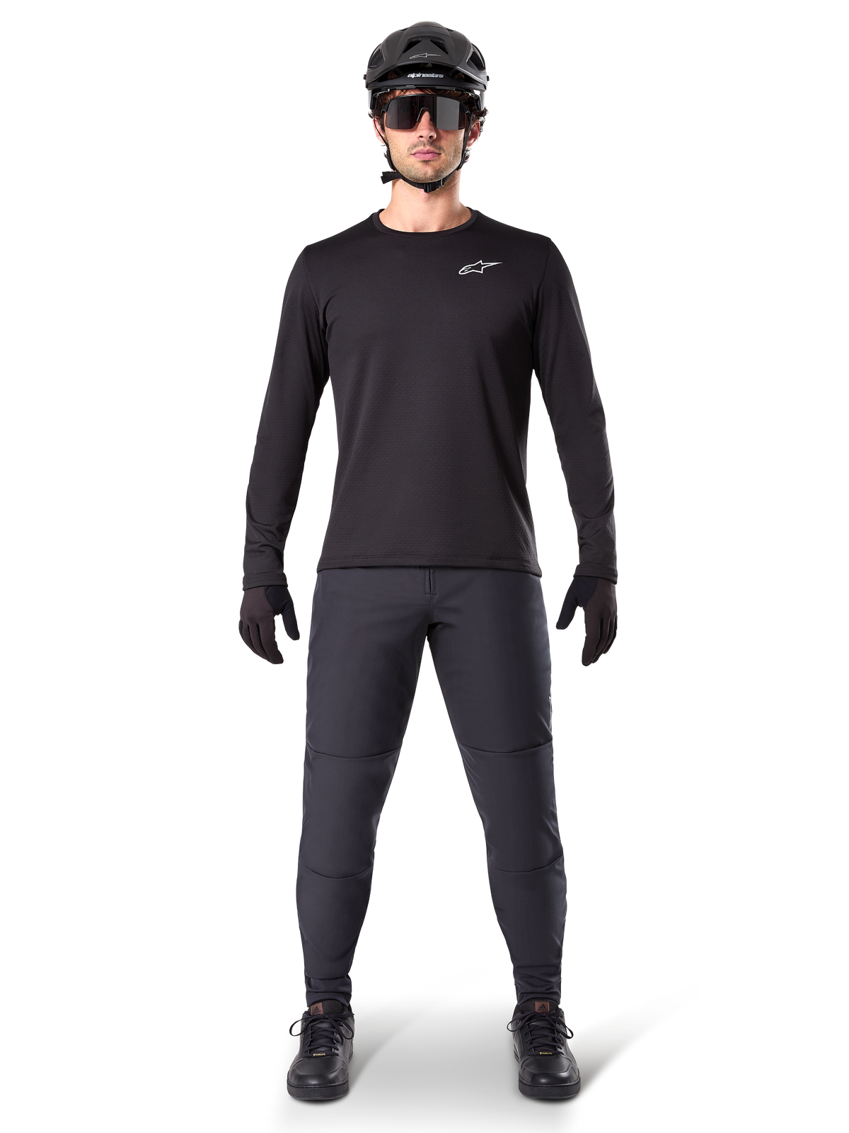 Alpinestars A-Dura Thermal Jersey, maillot de VTT à manches longues noir, porté avec un pantalon gris foncé, des gants noirs, un casque noir et des lunettes de soleil, logo Alpinestars blanc sur la poitrine, tenue coordonnée pour le VTT par temps froid