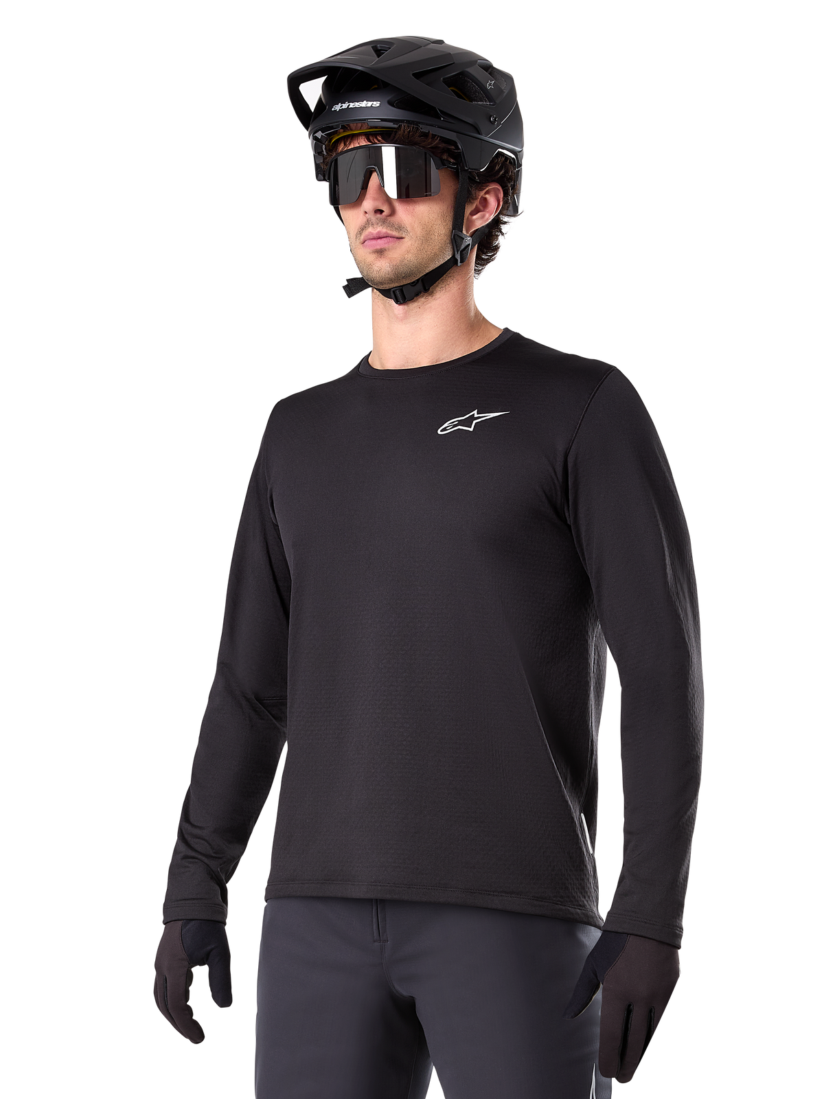 Alpinestars A-Dura Thermal Jersey, maillot de VTT à manches longues noir, logo blanc sur la poitrine, porté avec un casque et des gants noirs, design sportif et épuré pour le trail
