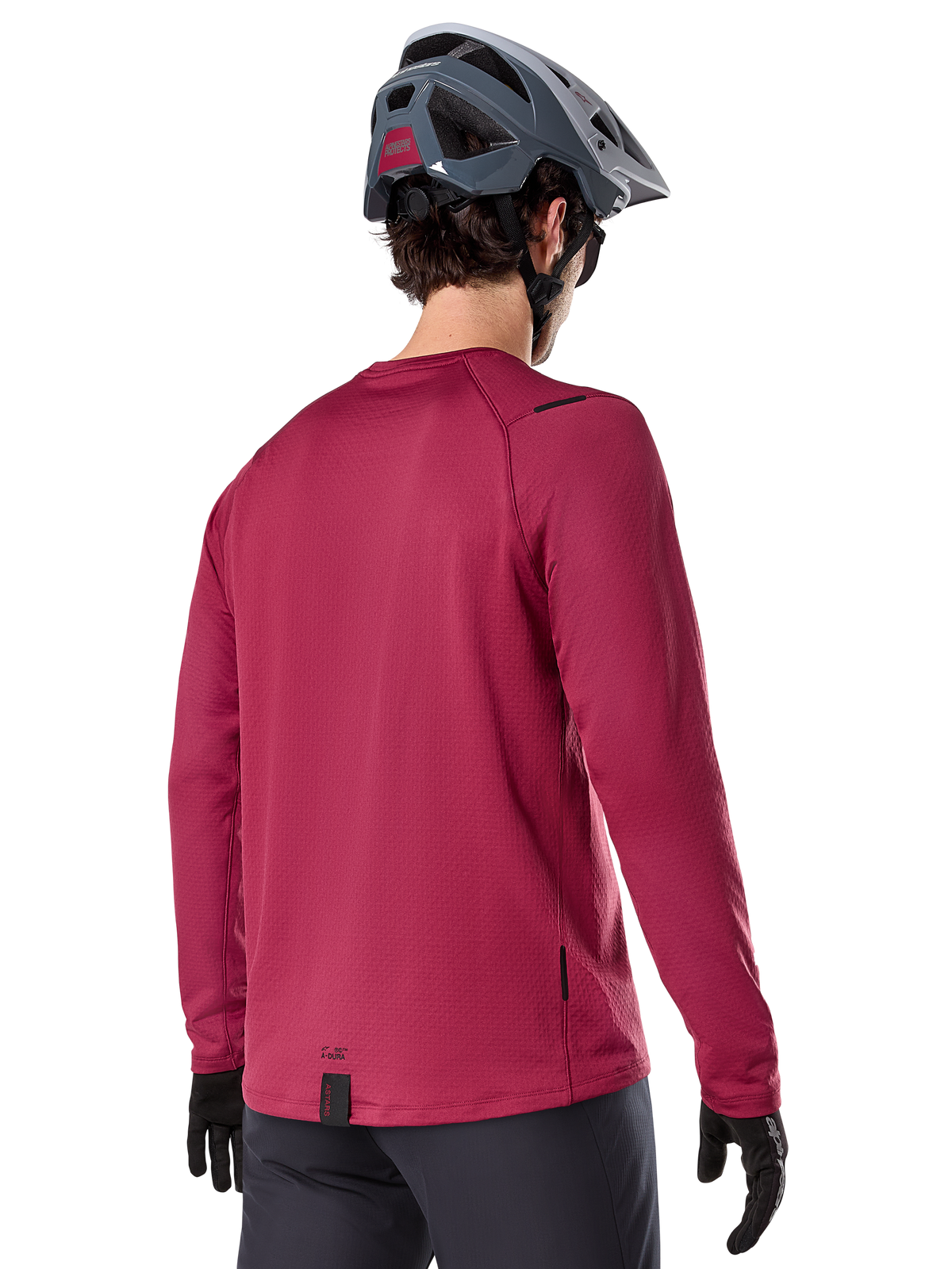 Maillot thermique Alpinestars A-Dura, maillot de VTT à manches longues, bordeaux, vue de dos d'un mannequin portant un casque de VTT gris et des gants noirs, doté d'un pan arrière allongé et de petits logos, conçu pour les sorties sur sentiers par temps froid.