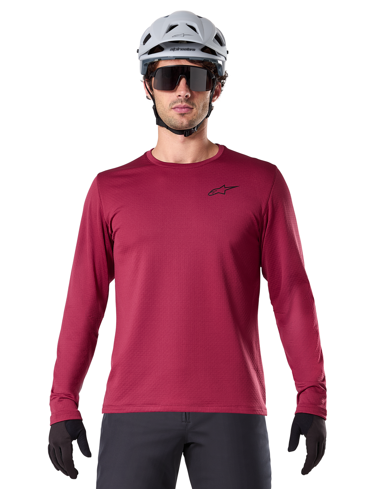 Maillot thermique Alpinestars A-Dura, maillot de VTT à manches longues pour homme, bordeaux, porté avec un casque gris et des lunettes de soleil noires, avec un petit logo étoile sur la poitrine, tissu polaire isolant pour le VTT par temps froid