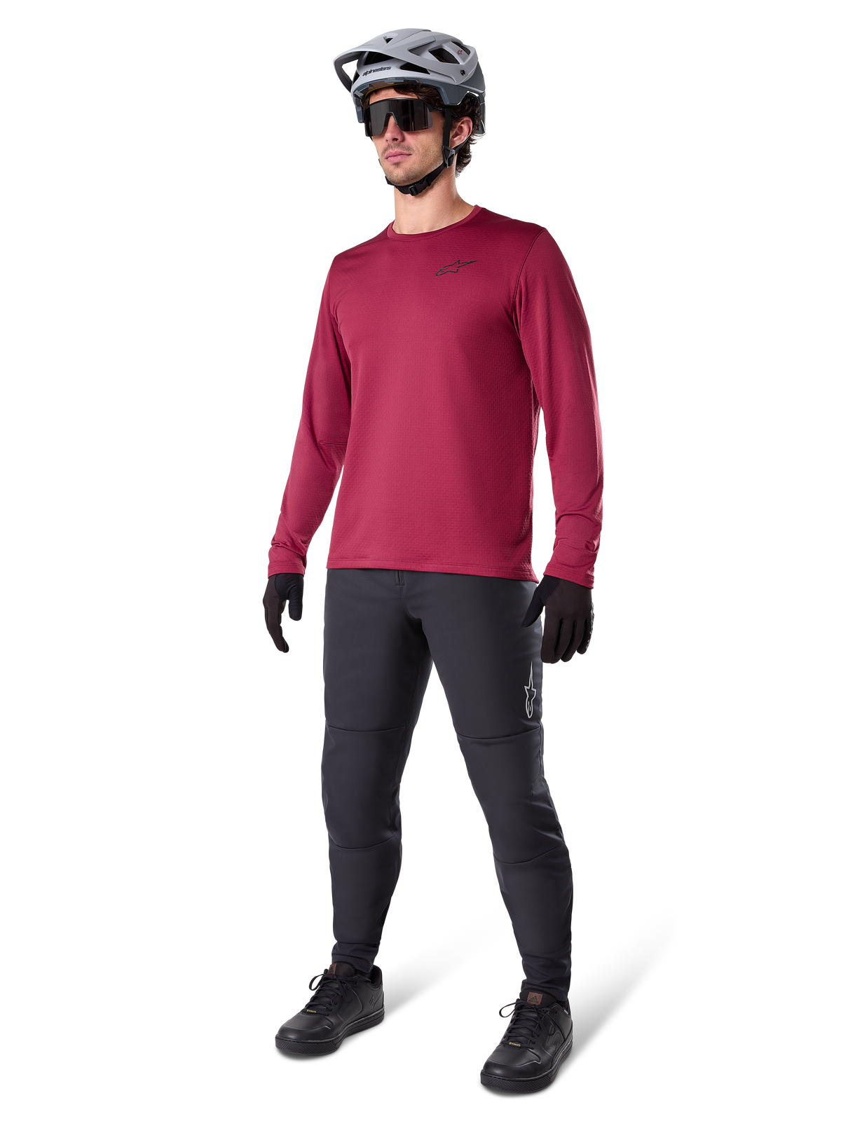 Maillot thermique Alpinestars A-Dura bordeaux, haut de cyclisme isolant à manches longues porté avec un pantalon de VTT gris foncé, des gants noirs et un casque gris, tenue complète de VTT pour temps froid, photo en studio