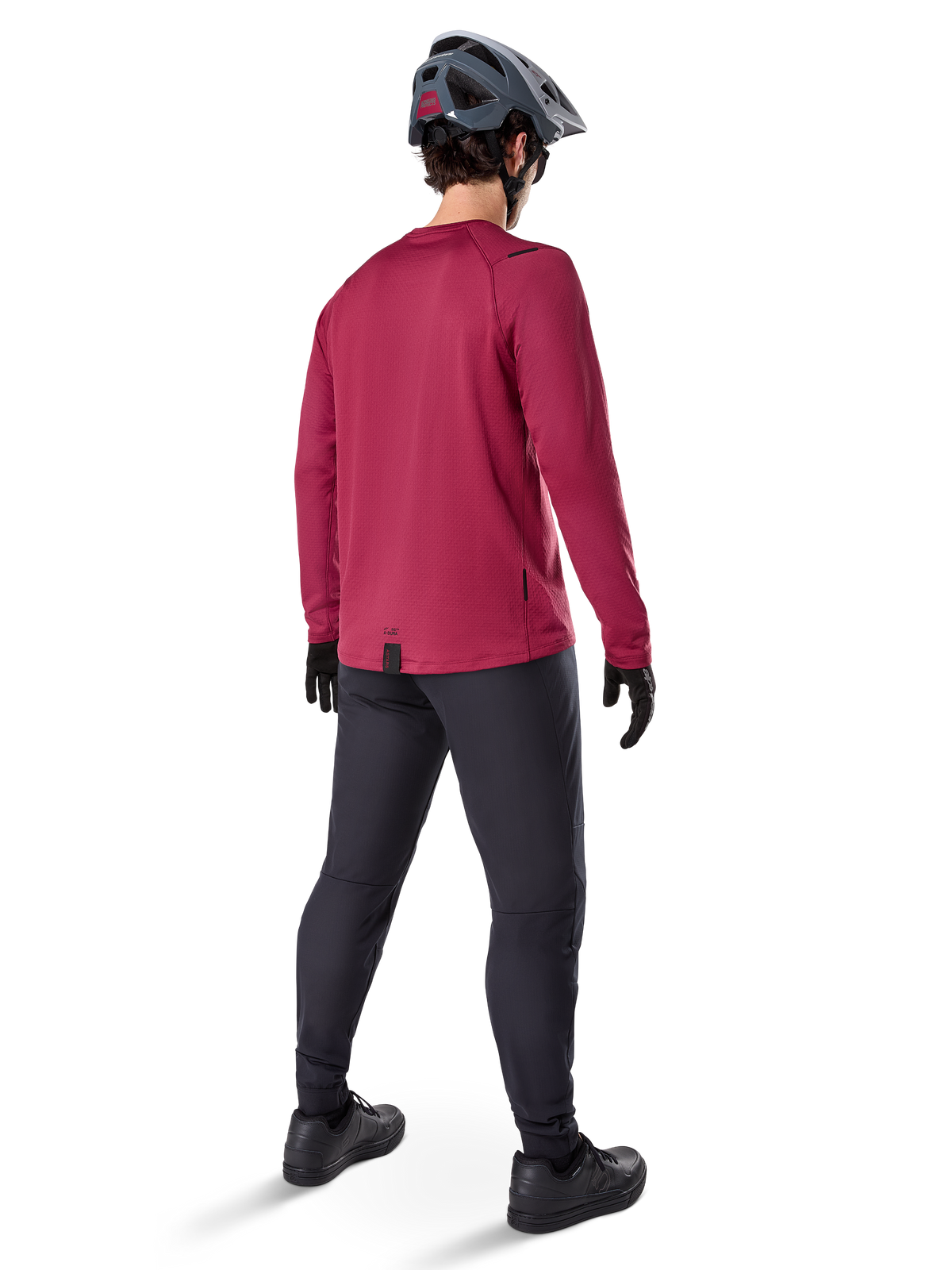 Alpinestars A-Dura Thermal Jersey, maillot de cyclisme à manches longues bordeaux, vue de dos, porté avec un pantalon de VTT noir et un casque gris, doté d'un pan arrière allongé pour une couverture arrière accrue, équipement de VTT pour temps froid