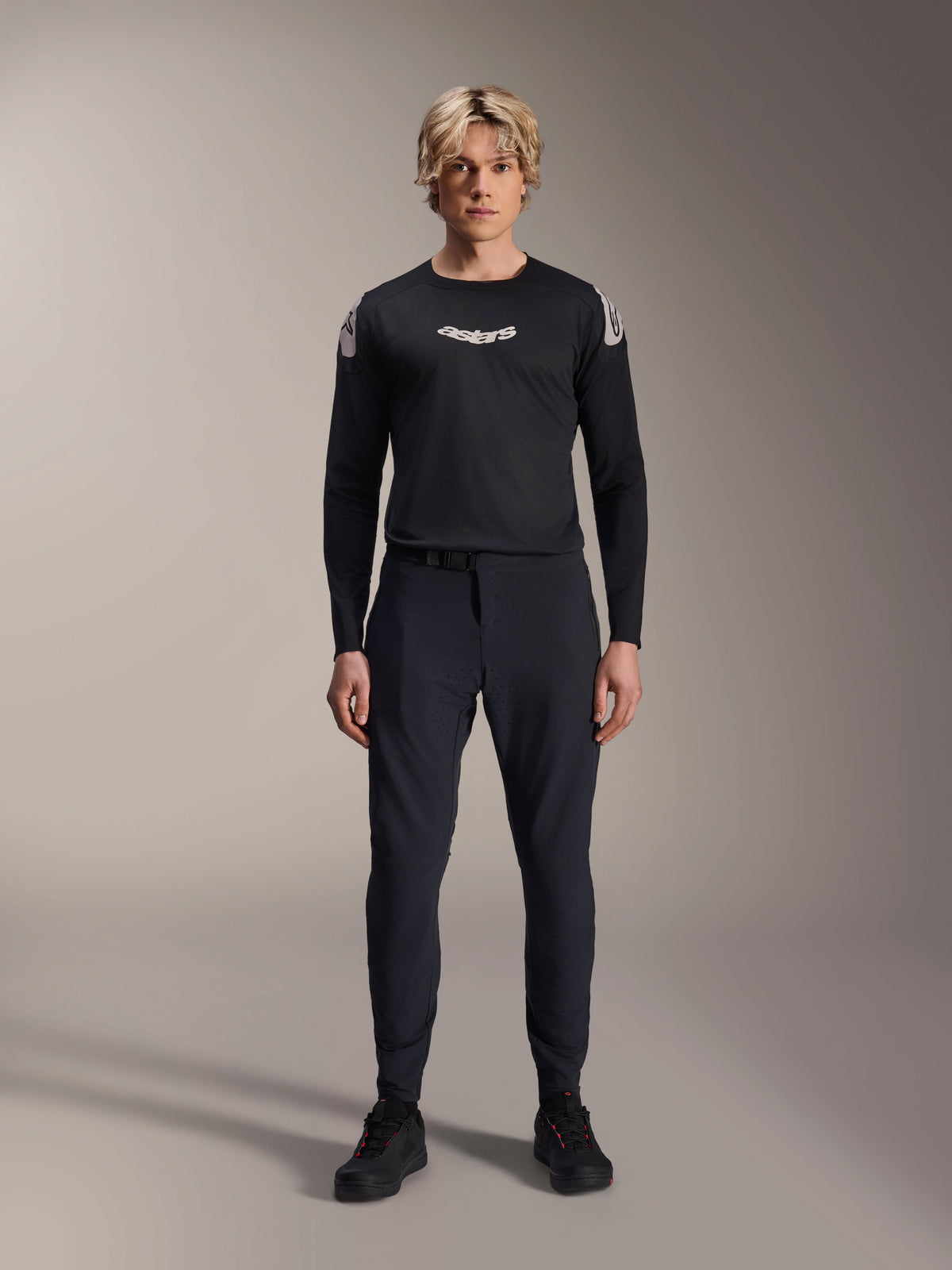 Maillot à manches longues Alpinestars A-Aria Polartec Elite noir, logo Astars blanc sur la poitrine et marquage sur les épaules, porté par un modèle masculin avec un pantalon technique de VTT et des chaussures noires, équipement de performance pour le VTT