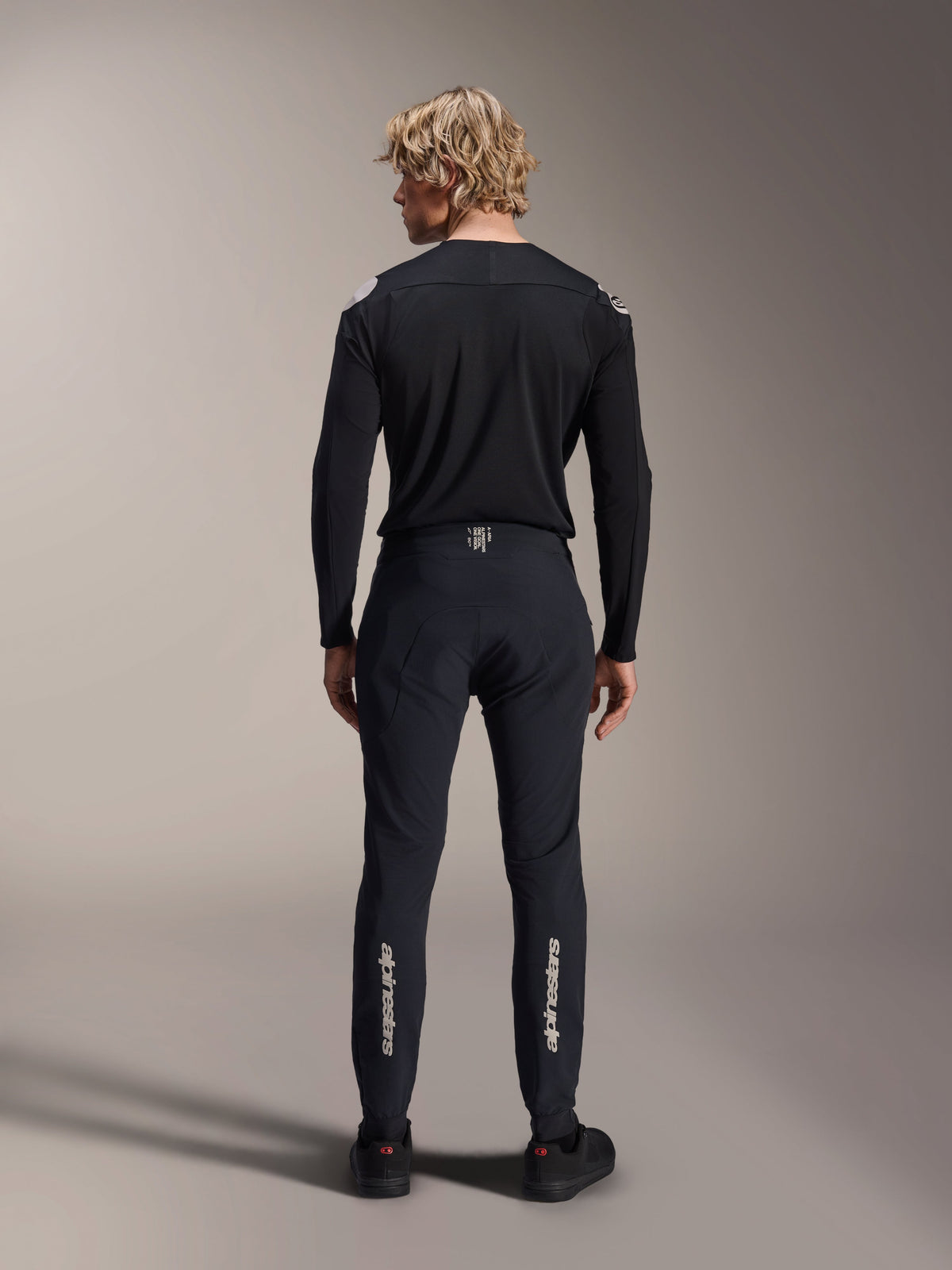 Maillot à manches longues Alpinestars A-Aria Polartec Elite, maillot de VTT noir, vue de dos porté avec un pantalon noir assorti, coupe performance pour le VTT, doté d'un tissu technique évacuant l'humidité et d'un marquage discret au bas du dos