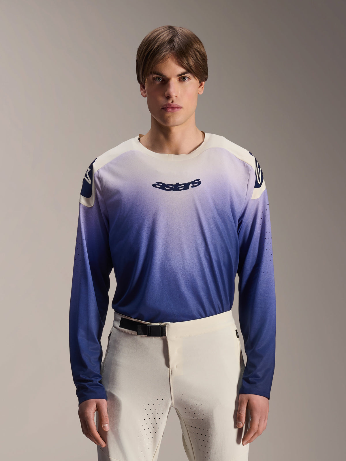 Alpinestars A-Aria Polartec Maker Elite Jersey, Long Sleeve MTB Jersey, Baja Blue with white-to-blue gradient, worn by a model with white pants, featuring dark blue chest logo and laser perforations on sleeves, performance mountain biking apparel