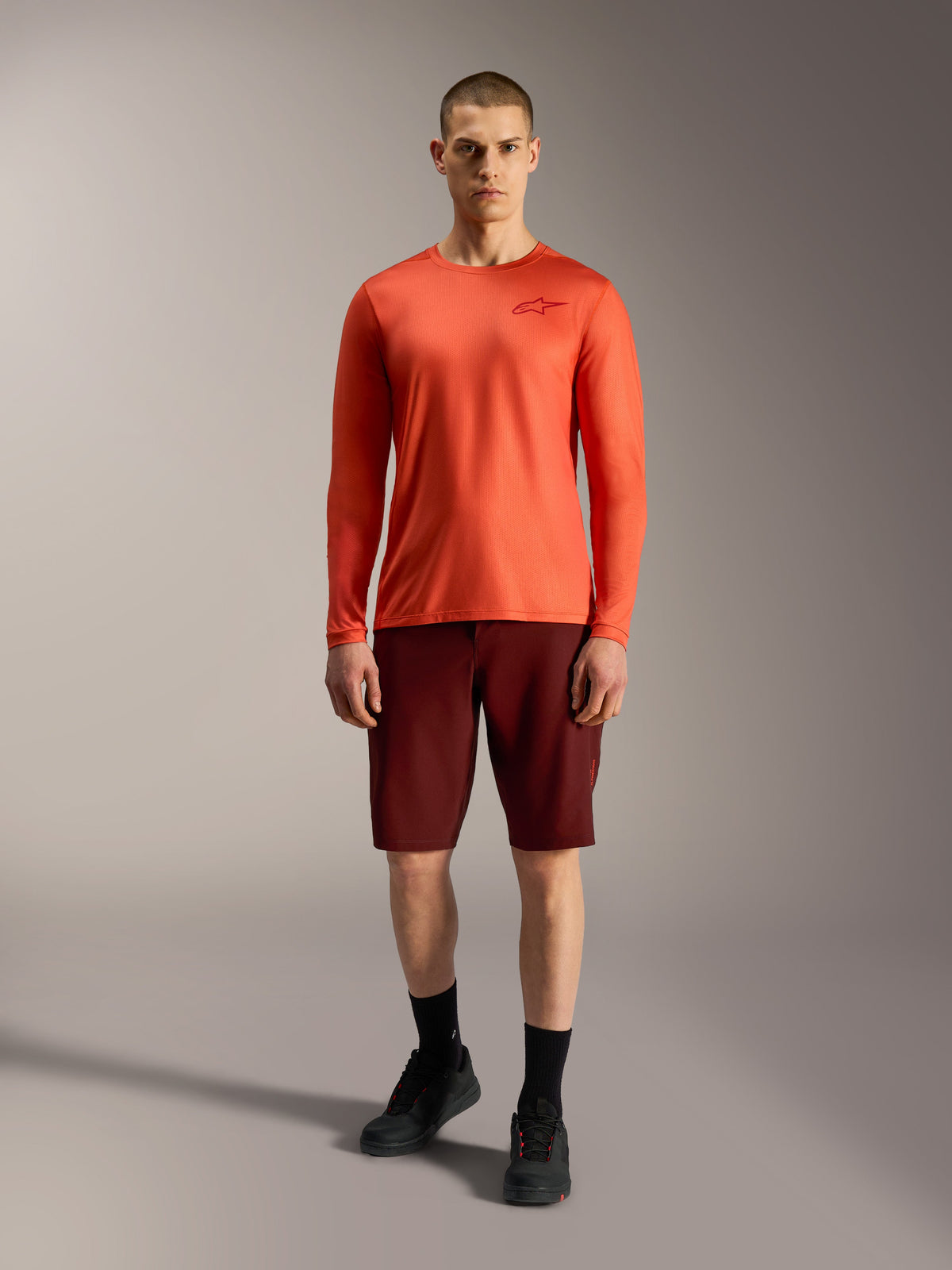 Shorts de VTT Alpinestars A-Dura Ride 2026 bordeaux et maillot orange à manches longues, tenue de performance homme.