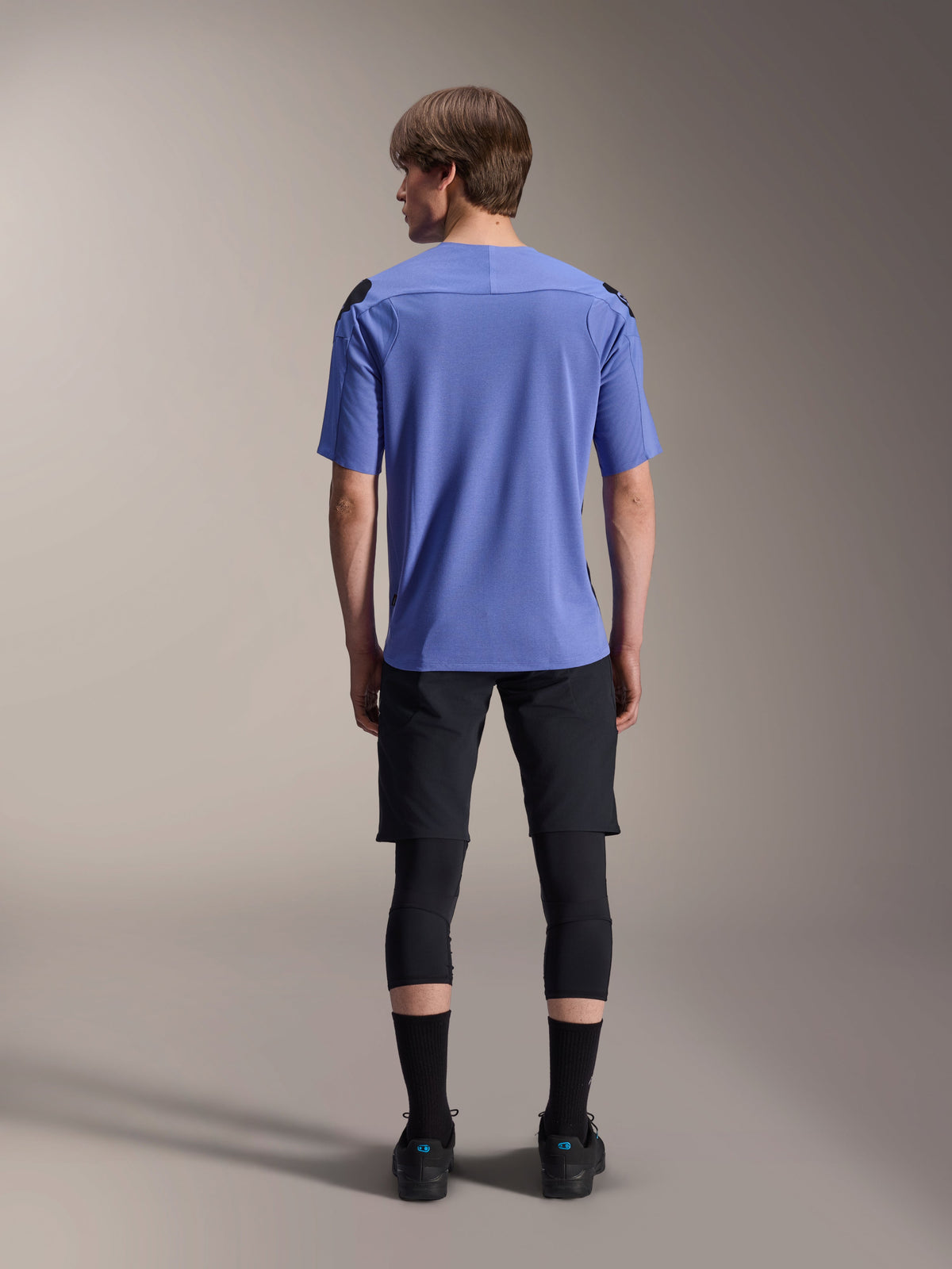 Maillot à manches courtes Alpinestars A-Aria Polartec Elite, Baja Blue, vue de dos, porté par un mannequin avec un short de VTT noir et des genouillères, vêtement de cyclisme haute performance