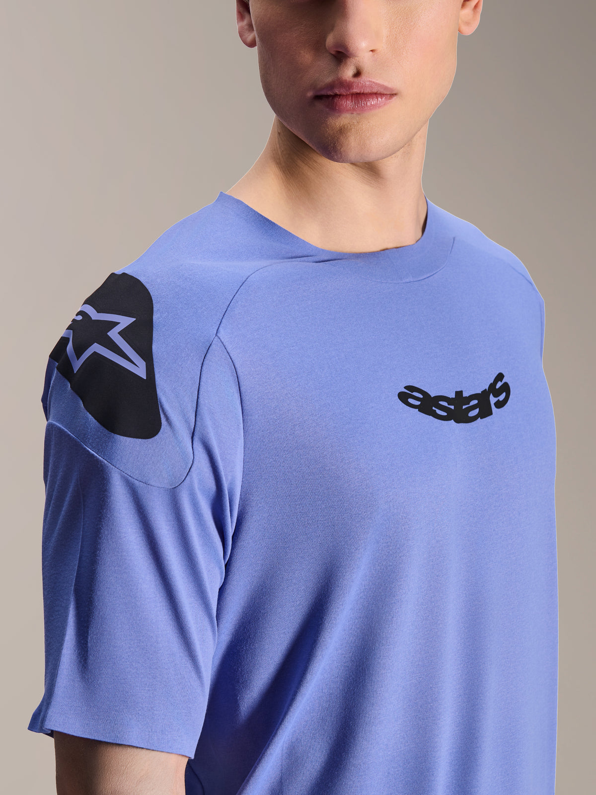 Alpinestars A-Aria Polartec Elite Jersey, maillot de VTT à manches courtes, bleu Baja, gros plan sur la poitrine et l'épaule présentant le logo astars noir et un motif graphique, tissu technique évacuant l'humidité pour le cyclisme tout-terrain
