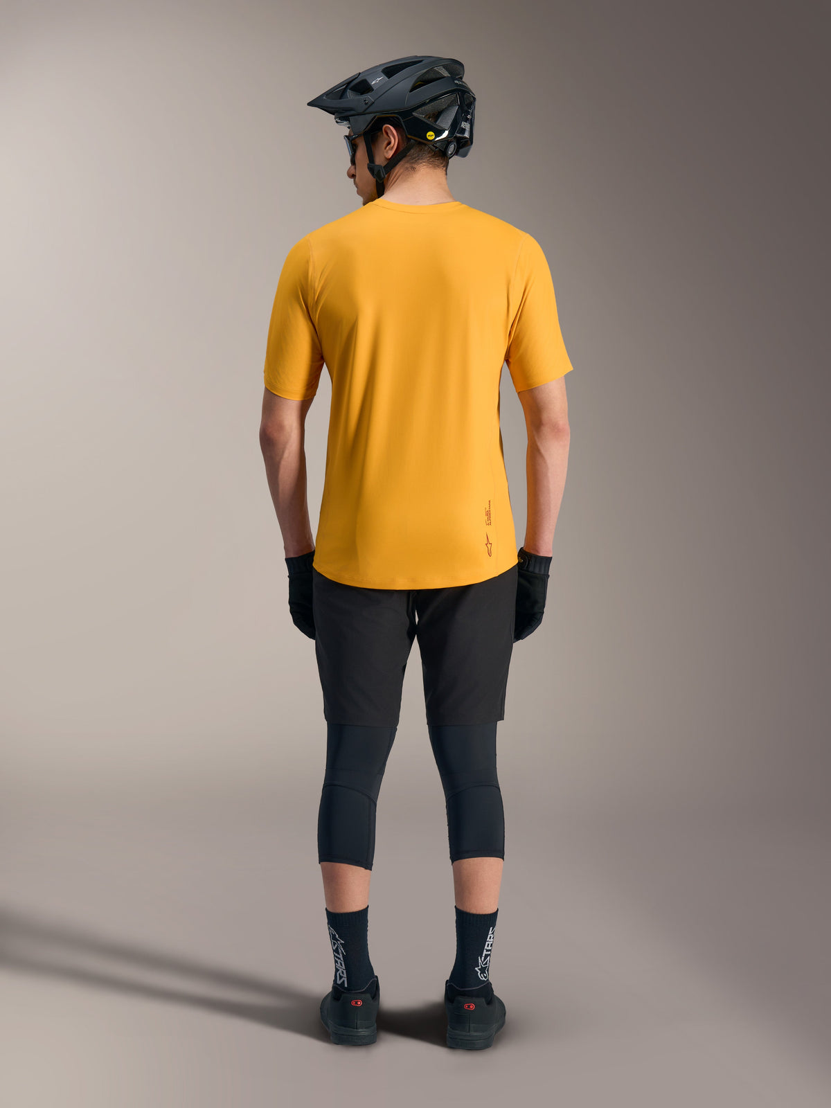 Maillot A-Dura Ride orange à manches courtes, vue arrière avec ourlet allongé et logo, style VTT décontracté.
