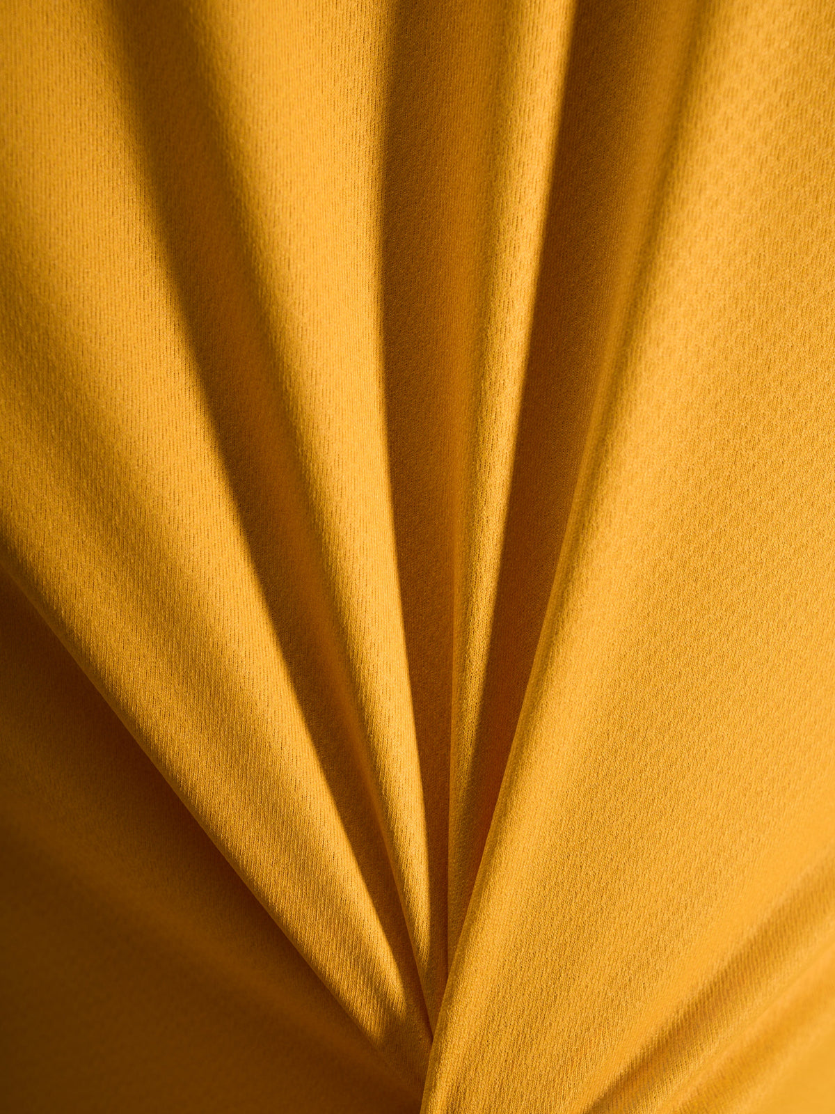 Gros plan sur la texture orange du maillot A-Dura Ride, matière jacquard légère en poly/spandex.