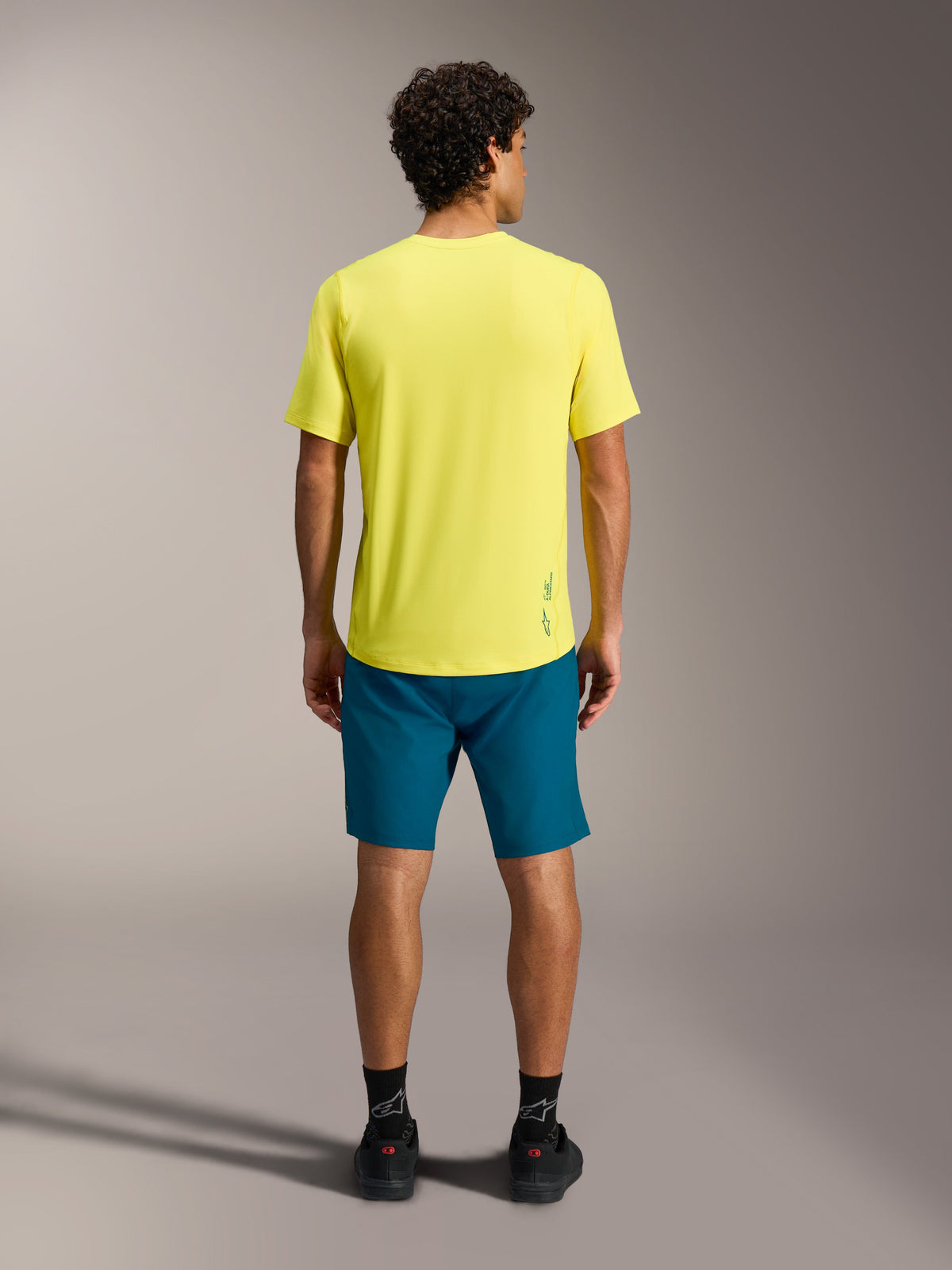 Maillot jaune A-Dura Ride SS et short bleu-vert A-Dura Ride vus de dos, équipement performant pour le VTT.
