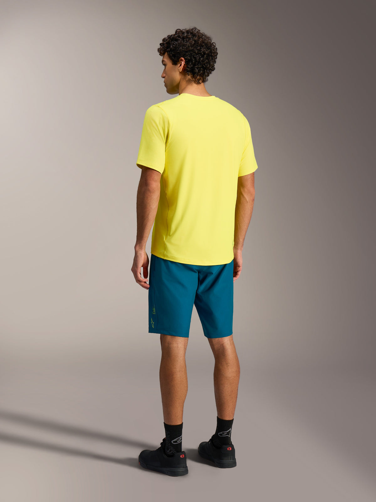 Maillot A-Dura Ride SS jaune et short A-Dura Ride bleu-vert, tenue de VTT Alpinestars vue de dos.