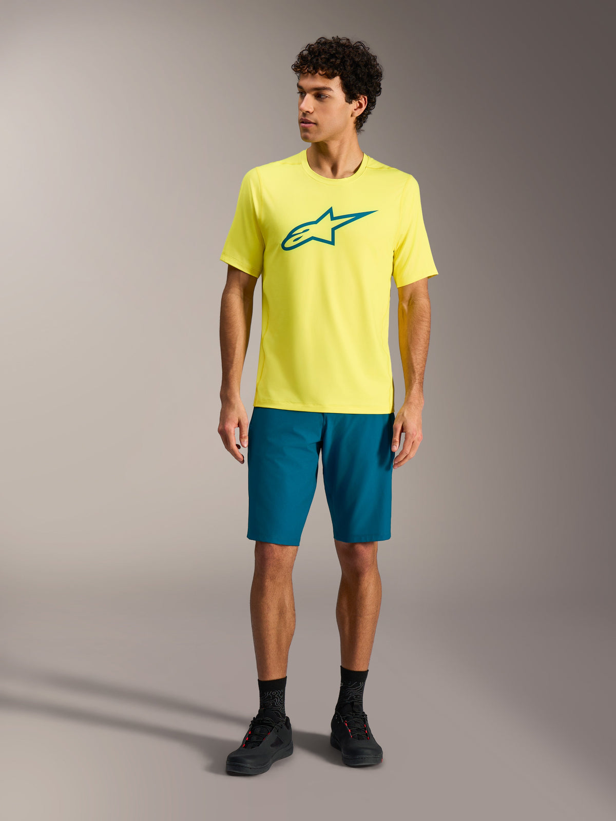 Maillot jaune Alpinestars A-Dura Ride SS et short bleu-vert, tenue de performance VTT en studio.