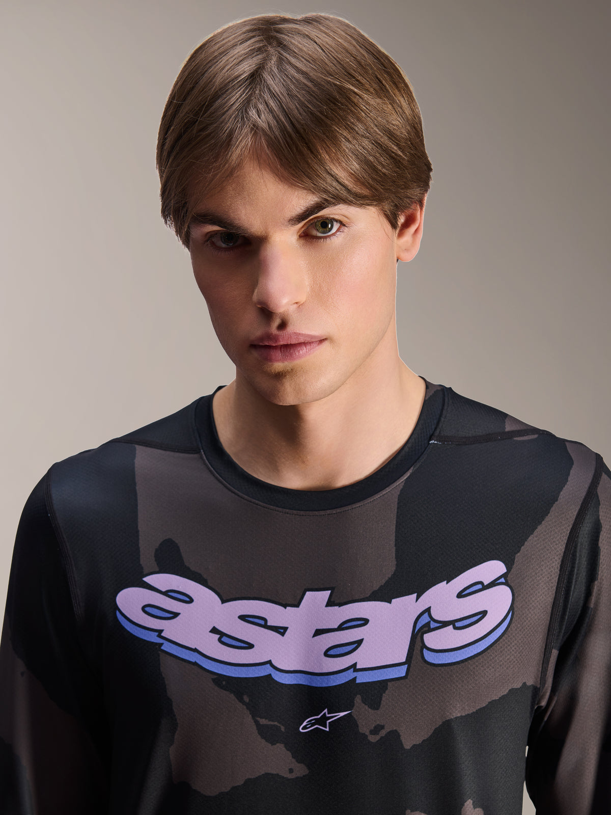 Maillot Alpinestars A-Dura Hollow Camo à manches longues, camouflage noir avec graphique 'astars' violet sur la poitrine, photo en studio d'un mannequin portant une tenue de VTT, style de vélo de montagne décontracté et technique
