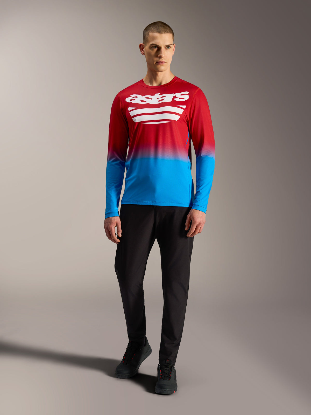 Maillot de VTT A-Dura ASTARS 2.0 à manches longues, dégradé rouge et bleu avec logos blancs, porté avec un pantalon noir.