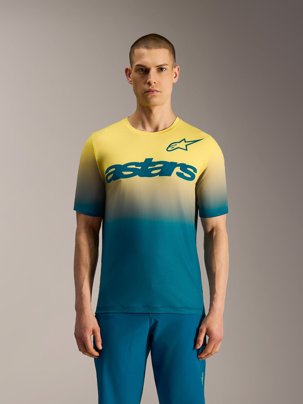 Maillot VTT A-Dura ASTARS 2.0 à manches courtes, dégradé bleu-vert à jaune fluo avec logo Astars sur la poitrine.