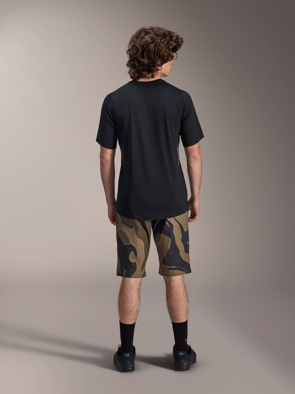 Alpinestars A-Dura Astar Short Sleeve Jersey, Black, back view on a model paired with camouflage patterned MTB shorts and black footwear, casual technical mountain bike apparel