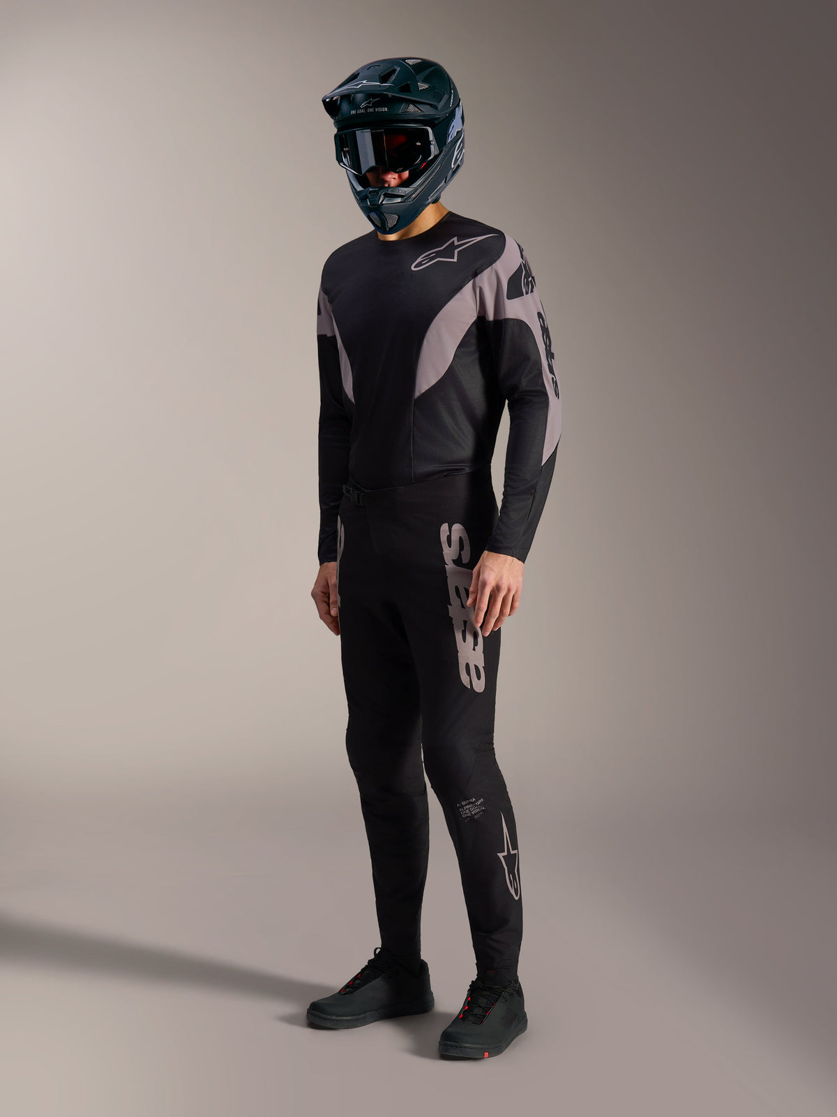 Tenue VTT A-Supra Elite noire et grise, avec maillot et pantalon stretch aux logos Alpinestars audacieux.