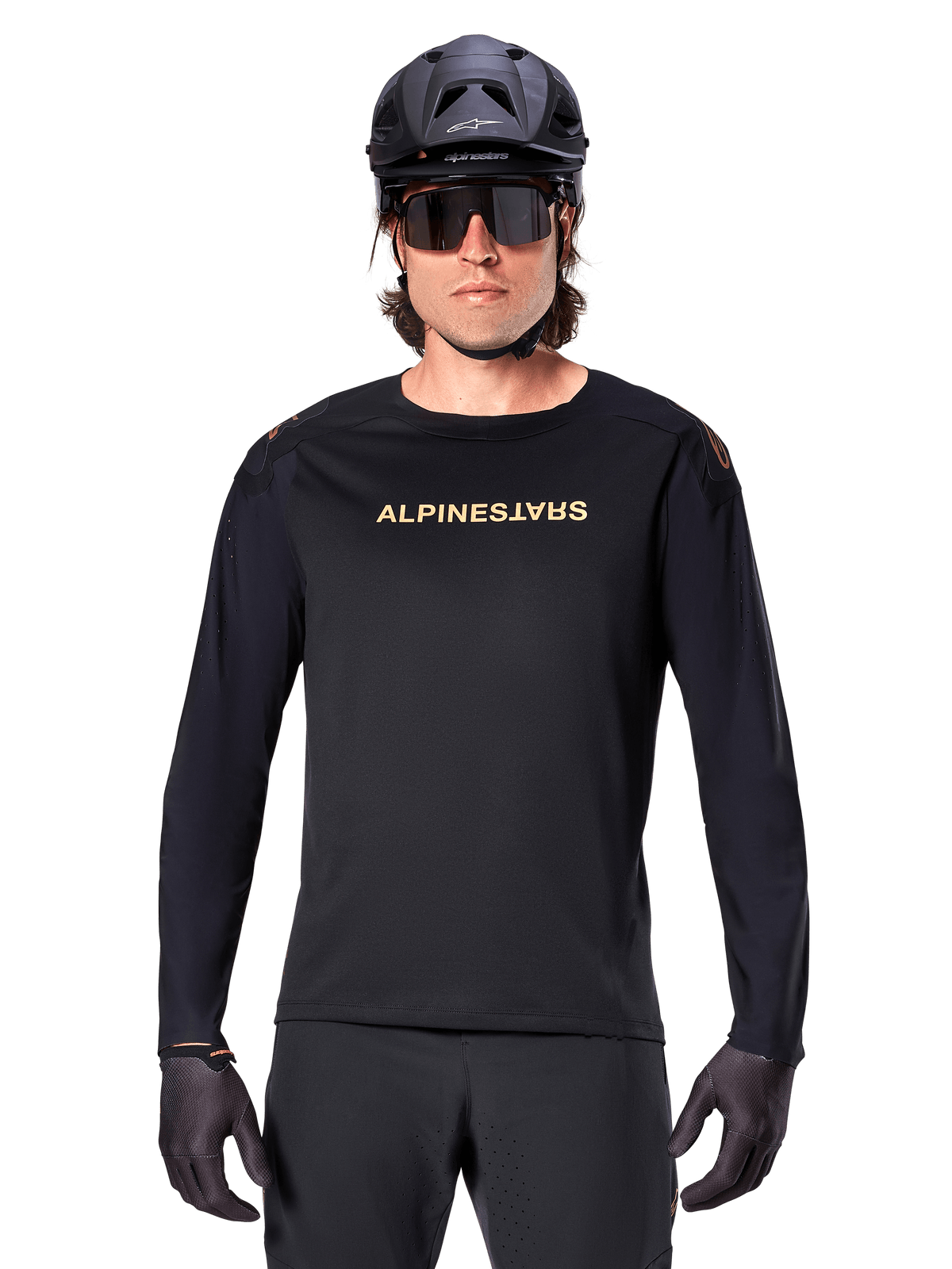 Maillot à manches longues Alpinestars A-Aria Polartec Switch, noir, logo Alpinestars doré sur la poitrine, porté avec un casque de VTT noir, des lunettes de soleil foncées et des gants noirs, équipement de trail VTT professionnel