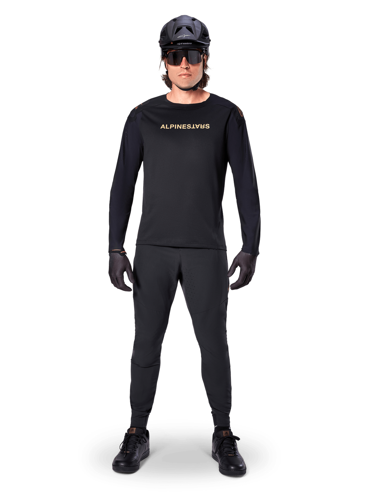 Maillot à manches longues Alpinestars A-Aria Polartec Switch, noir, porté par un cycliste avec un pantalon technique noir assorti, un casque noir, des lunettes de soleil et des gants noirs, équipement de VTT haute performance pour les sentiers tout-terrain