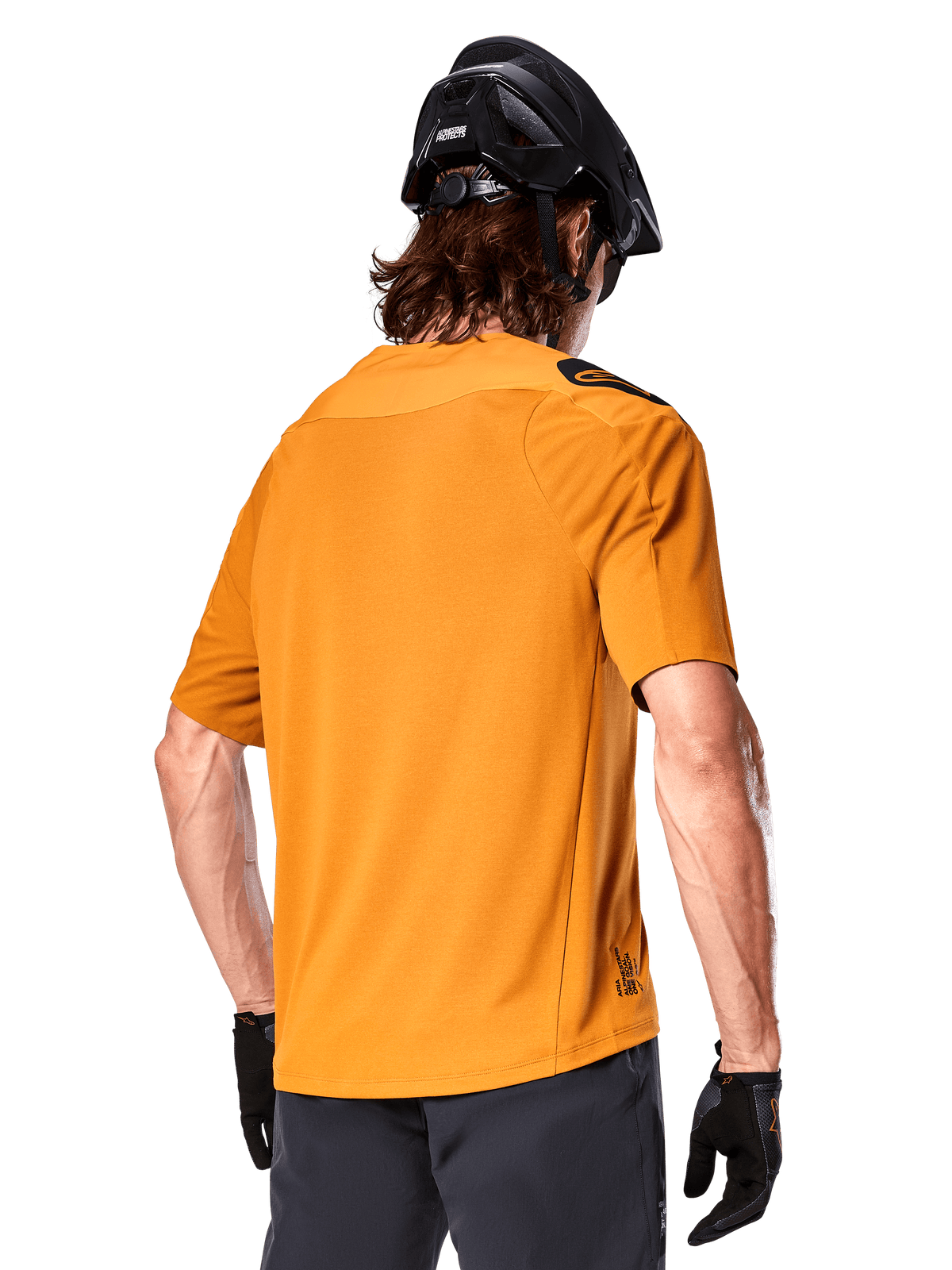 Maillot Alpinestars A-Aria Polartec Switch, maillot de VTT à manches courtes, or foncé, vue de dos montrant la coupe performance, porté avec un casque noir et un short gris, vêtement de trail durable et respirant