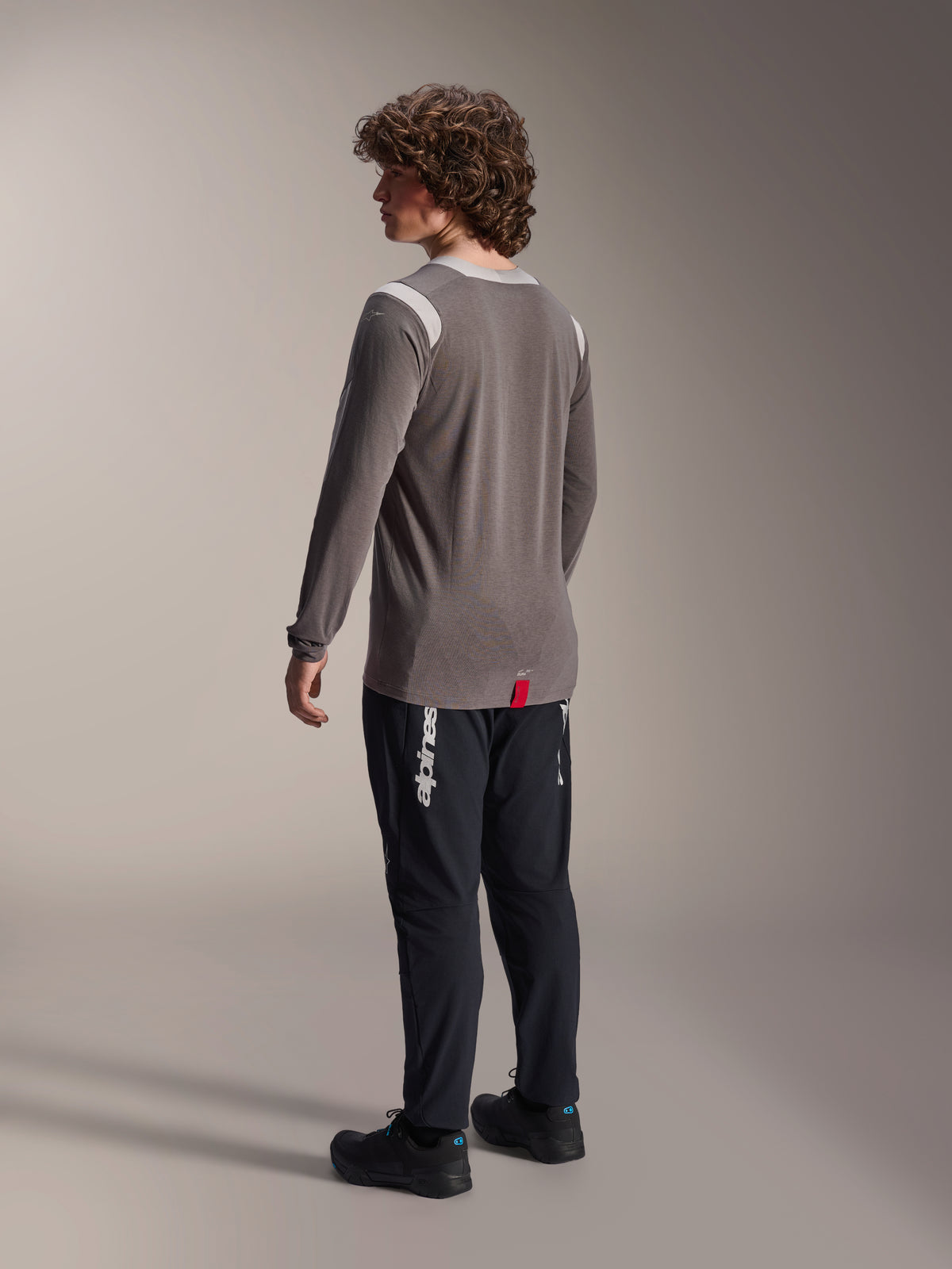 Maillot à manches longues Alpinestars A-Dura Dri-Wool gris et pantalon A-Dura Elite noir, vue arrière du modèle, logo Alpinestars blanc sur la jambe, équipement de VTT technique pour le tout-terrain
