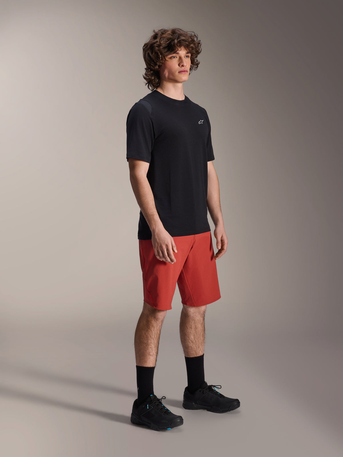 Mannequin homme portant le short Alpinestars A-Dura Elite en orange foncé et le maillot à manches courtes A-Dura Dri Wool en noir, équipement de performance pour VTT, avec chaussettes et chaussures noires, design athlétique pour le cyclisme tout-terrain.