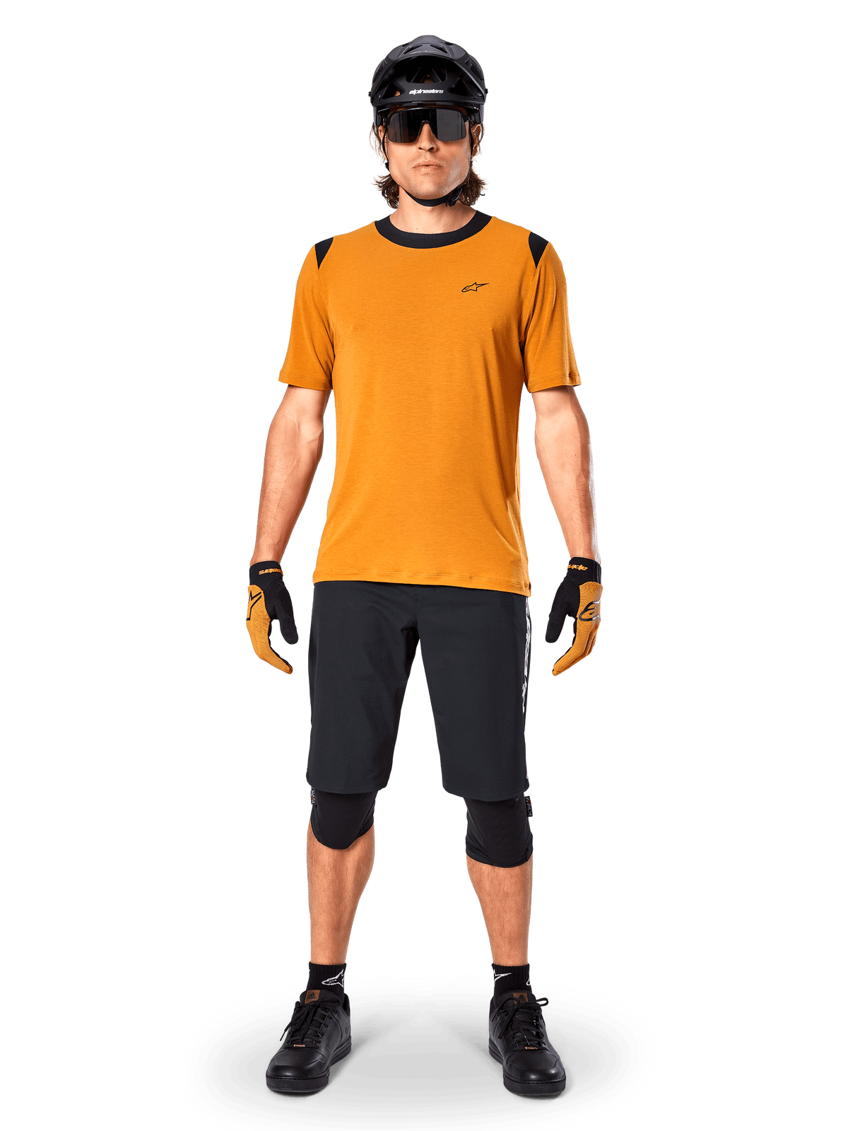 Maillot à manches courtes Alpinestars A-Dura Dri Wool en Dark Gold, maillot de VTT porté avec un short noir et un équipement de protection, tissu jaune moutarde avec col et accents noirs aux épaules, vêtement de cyclisme haute performance pour le trail