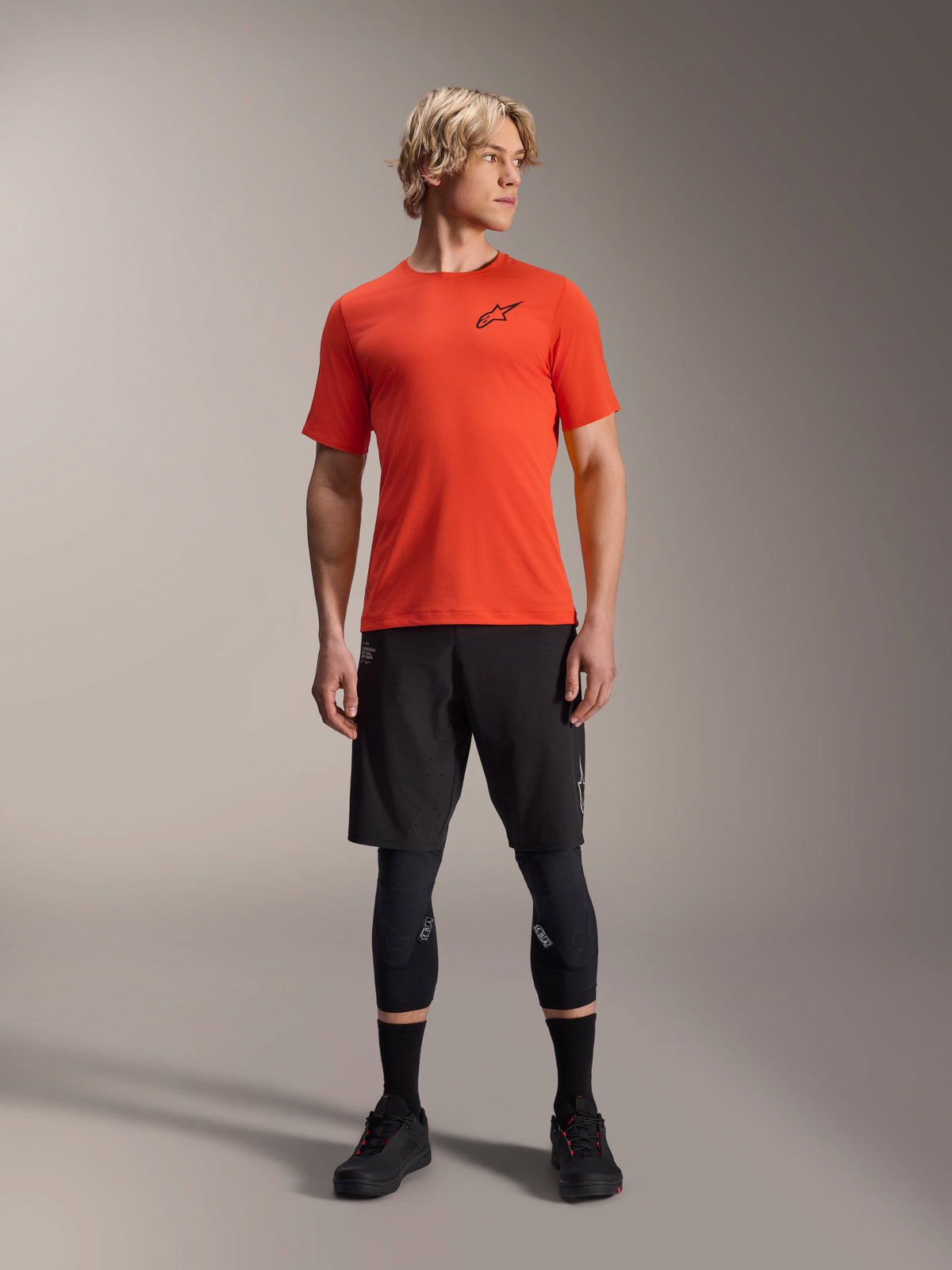 Alpinestars A-Aria Astar Short Sleeve Jersey, Spicy Orange, worn by model with black mountain bike shorts and knee guards, lightweight and breathable performance cycling apparel for MTB