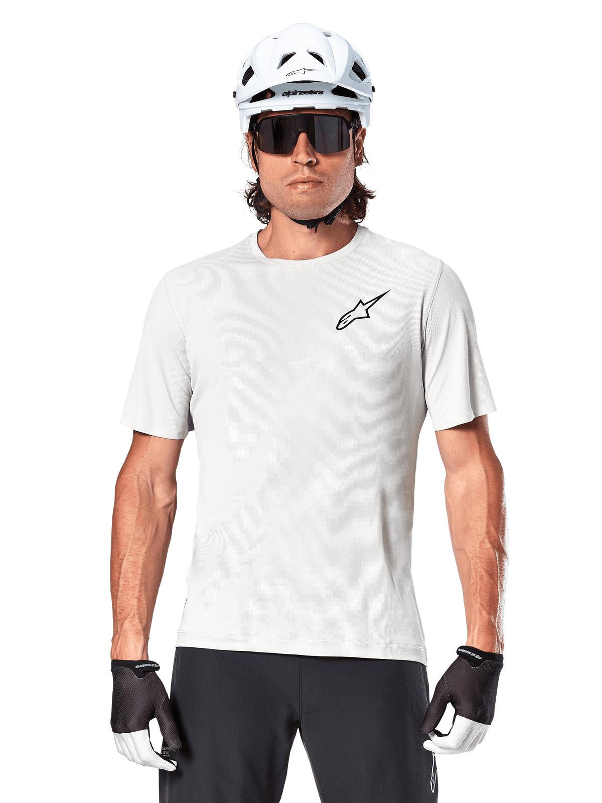 Cycliste portant le maillot à manches courtes Alpinestars A-Aria Astar, White Dove avec petit logo Astar noir sur la poitrine, casque de cyclisme blanc, lunettes de soleil noires et gants noirs et blancs, équipement VTT performant pour la conduite tout-terrain