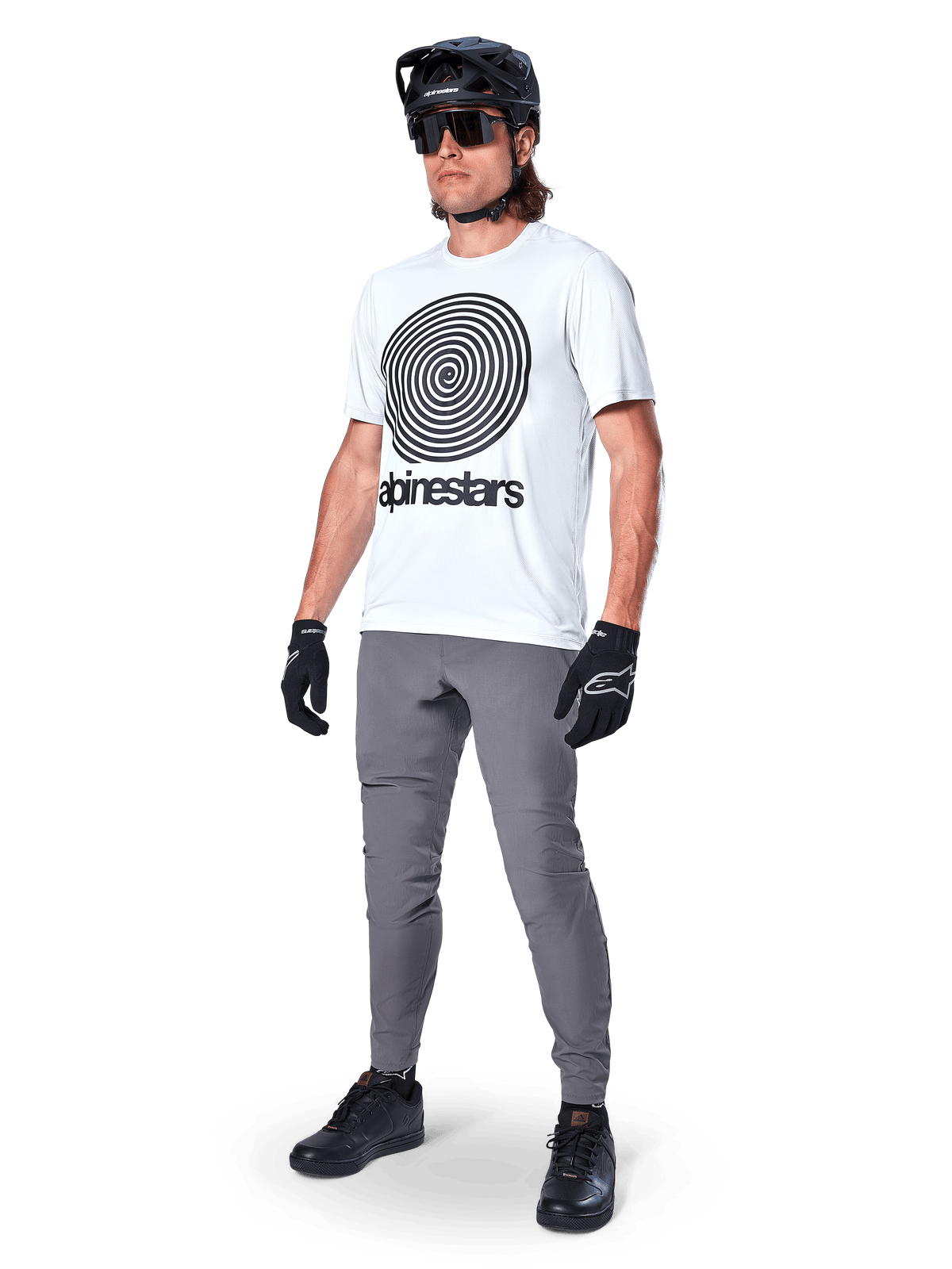 Alpinestars A-Dura Oscar Jersey - Short Sleeve, White Dove with large black spiral graphic, worn by a rider with grey MTB pants, black helmet, and gloves, performance cycling apparel for off-road riding