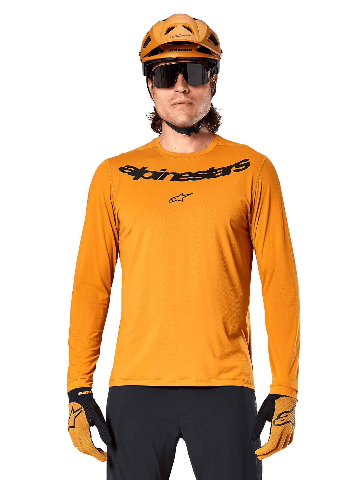 Maillot à manches longues Alpinestars A-Dura Rocker en Dark Gold, avec un logo noir sur la poitrine, porté avec un casque et des gants dorés assortis pour la performance en VTT.