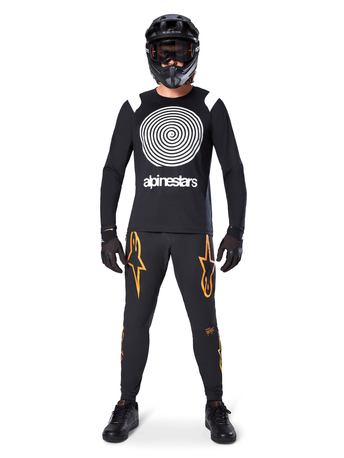 Mannequin homme portant un équipement complet de VTT, maillot à manches longues Alpinestars A-Supra Oscar noir avec graphique en spirale blanc sur la poitrine, pantalon noir avec logos étoiles orange, casque intégral noir et masque, gants et chaussures noirs, tenue coordonnée pour la pratique du VTT en gravité