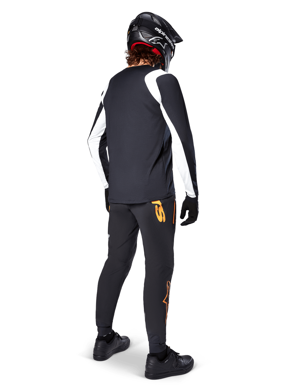 Maillot à manches longues Alpinestars A-Supra Oscar, noir avec empiècements blancs sur les manches, porté de dos par un cycliste VTT avec un casque intégral noir et un pantalon noir arborant des logos orange, vêtement de cyclisme pour le VTT de descente (gravity)