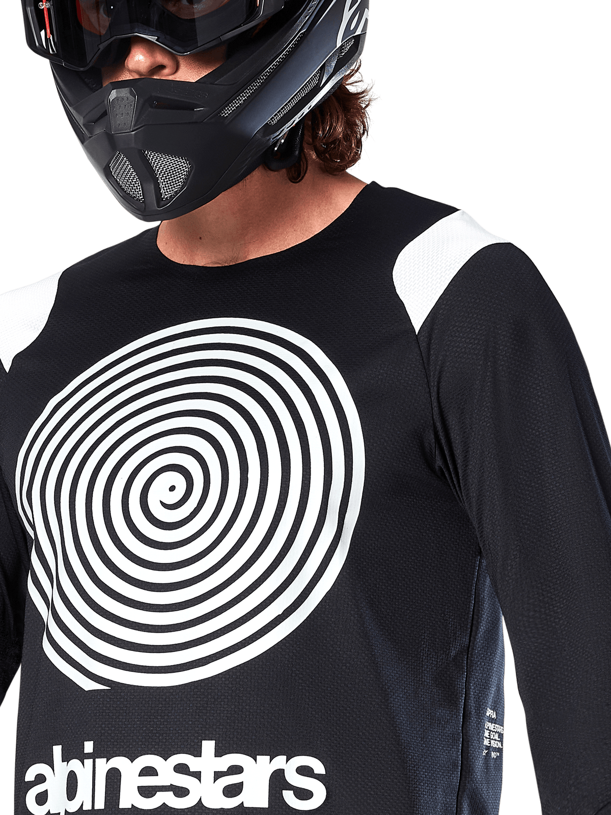 Maillot Alpinestars A-Supra Oscar, manches longues, noir, avec un grand graphique en spirale Oscar blanc sur la poitrine et le logo de la marque, porté par un pilote avec un casque intégral noir et un masque, vêtement de VTT haute performance pour la pratique du gravity