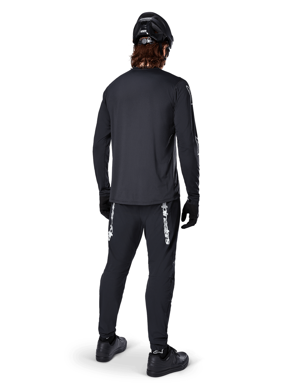 Maillot à manches longues Alpinestars A-Dura Switch, noir, vue arrière sur un cycliste, porté avec un pantalon noir arborant le marquage Alpinestars blanc, un casque noir et des gants, doté d'un pan arrière allongé pour une meilleure protection, vêtement de VTT haute performance