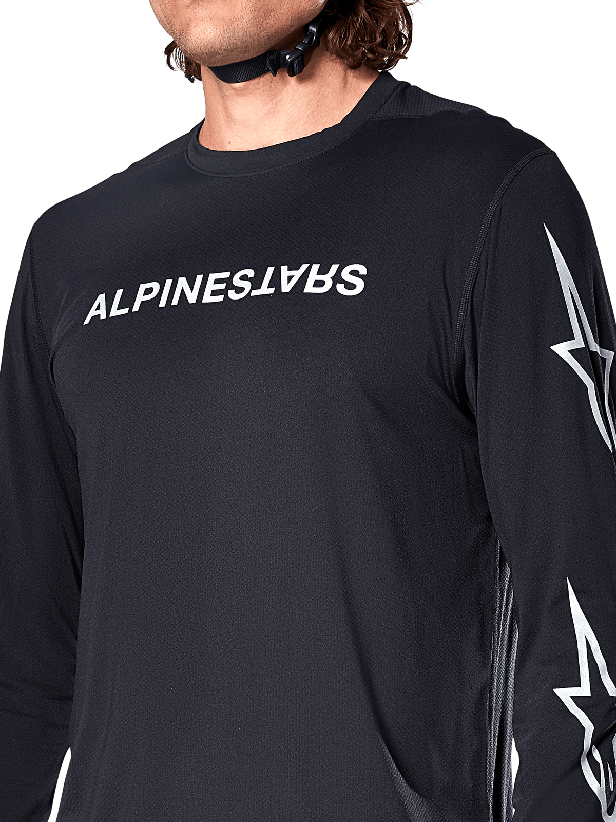 Maillot à manches longues Alpinestars A-Dura Switch, noir, avec logo Alpinestars blanc sur la poitrine et logos étoiles sur la manche, porté par un cycliste avec une sangle de casque visible, vêtement technique de VTT