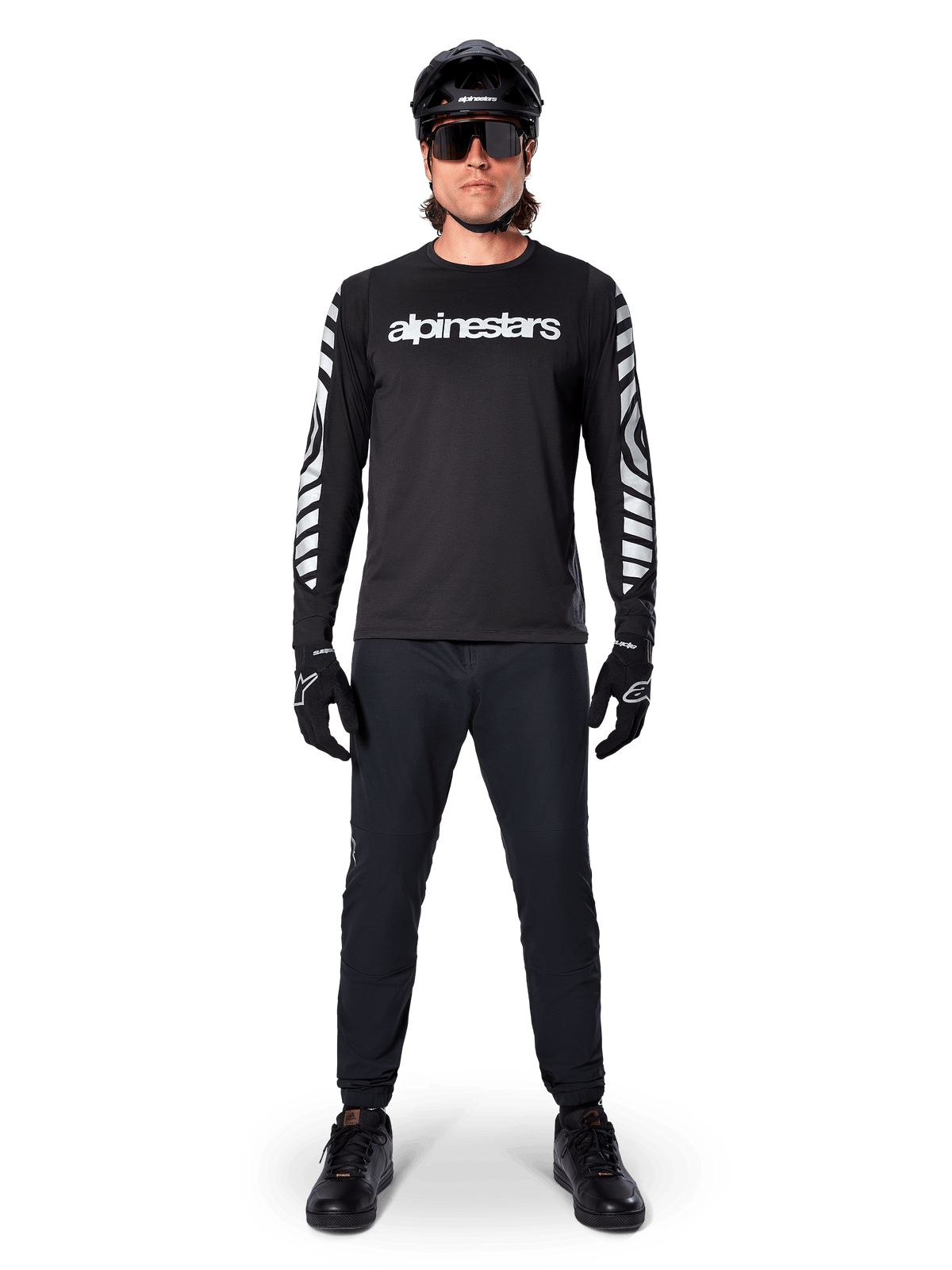 Alpinestars A-Dura Dri Oscar Long Sleeve Jersey in Black Reflective, worn with a black helmet and sunglasses, featuring white chest logo and reflective graphic patterns on the sleeves, MTB gear for off-road riding