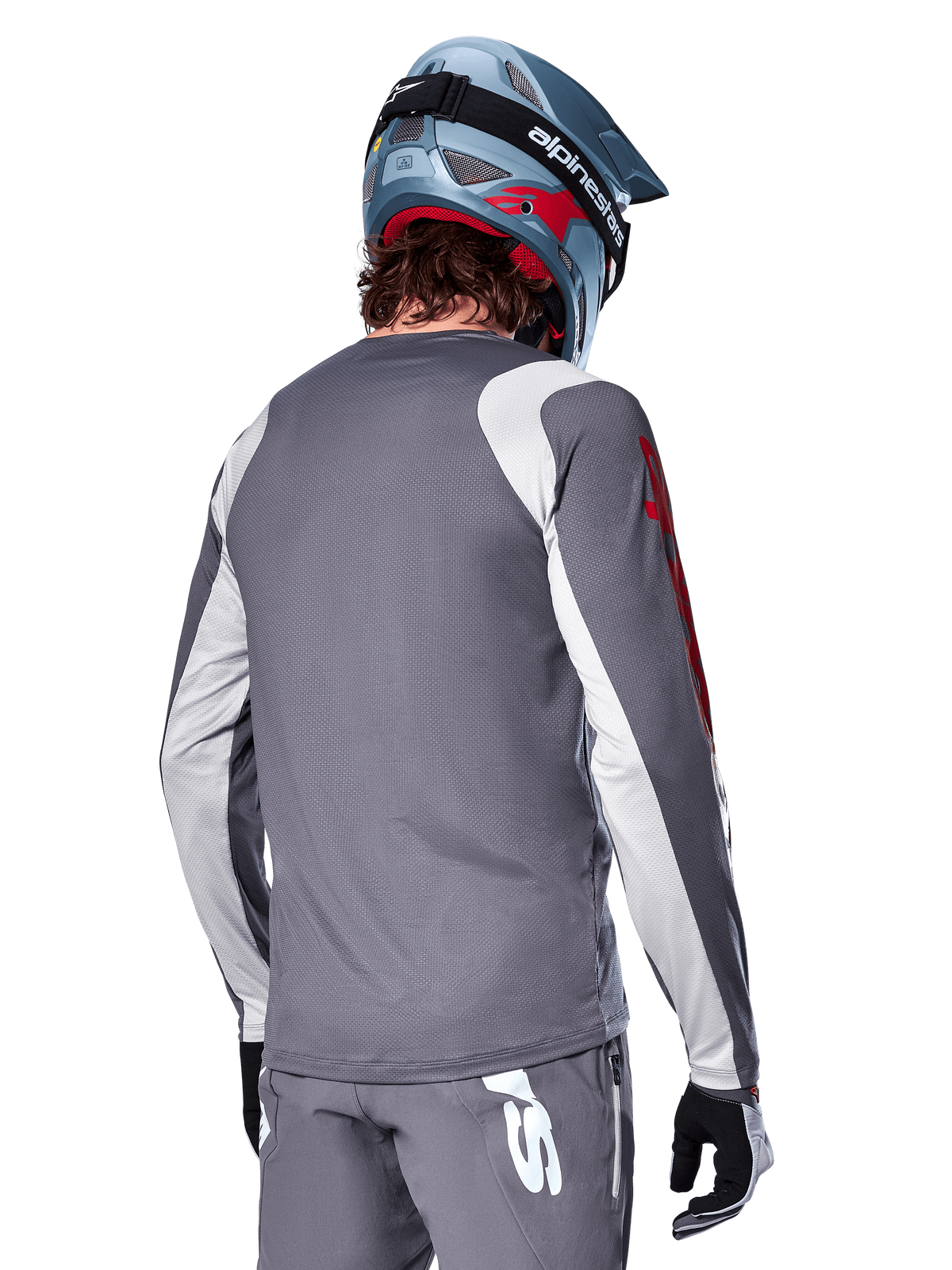 Maillot à manches longues Alpinestars A-Supra Astar, gris foncé avec empiècements gris clair aux épaules et aux bras, vue arrière d'un cycliste portant un casque de VTT intégral bleu et un pantalon gris, vêtement de cyclisme VTT haute performance