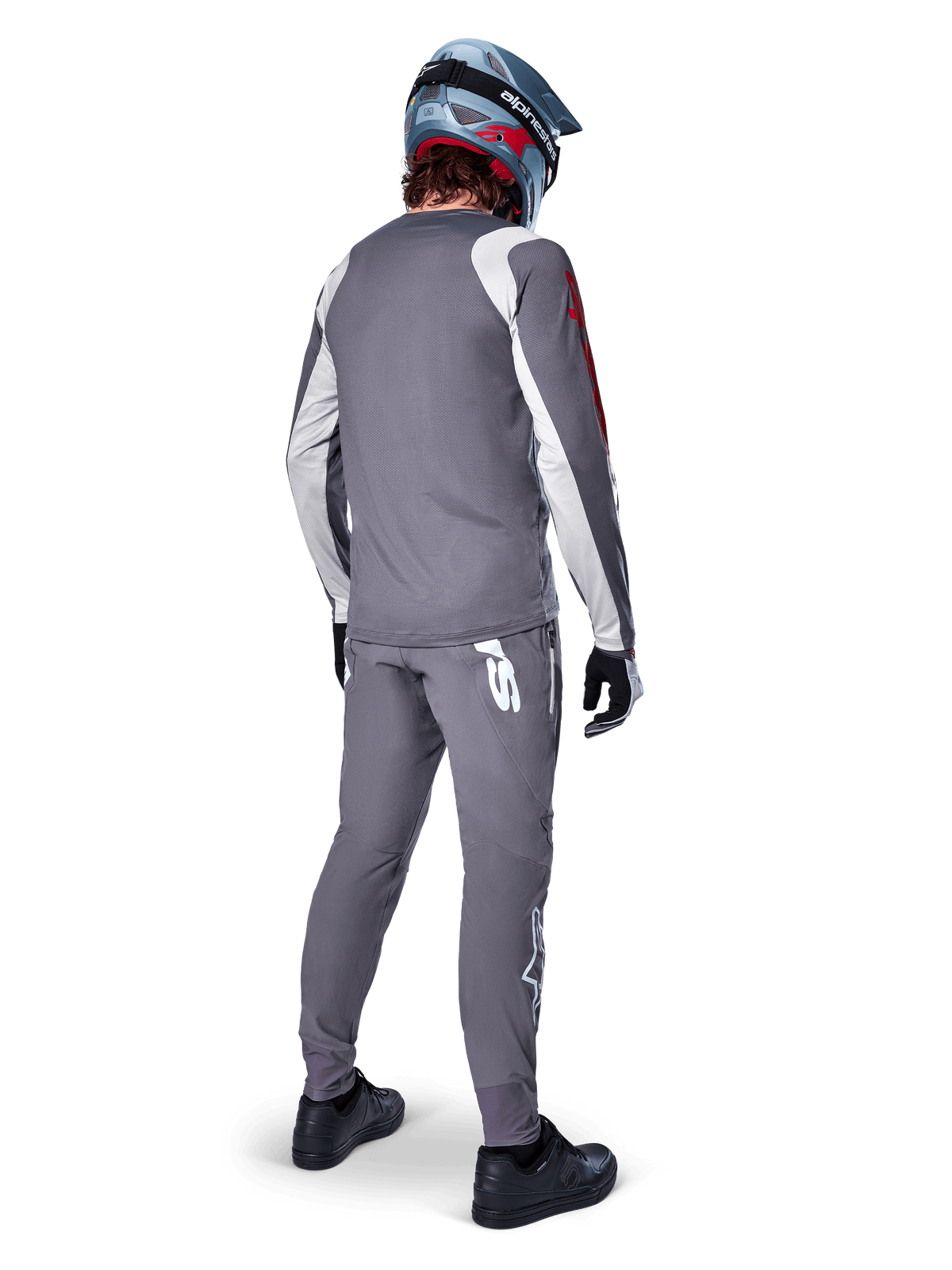 Maillot Alpinestars A-Supra Astar, maillot de VTT à manches longues, gris foncé avec accents blancs sur les manches et logo rouge, vue de dos d'un pilote portant un pantalon gris assorti et un casque intégral bleu, vêtements de cyclisme haute performance