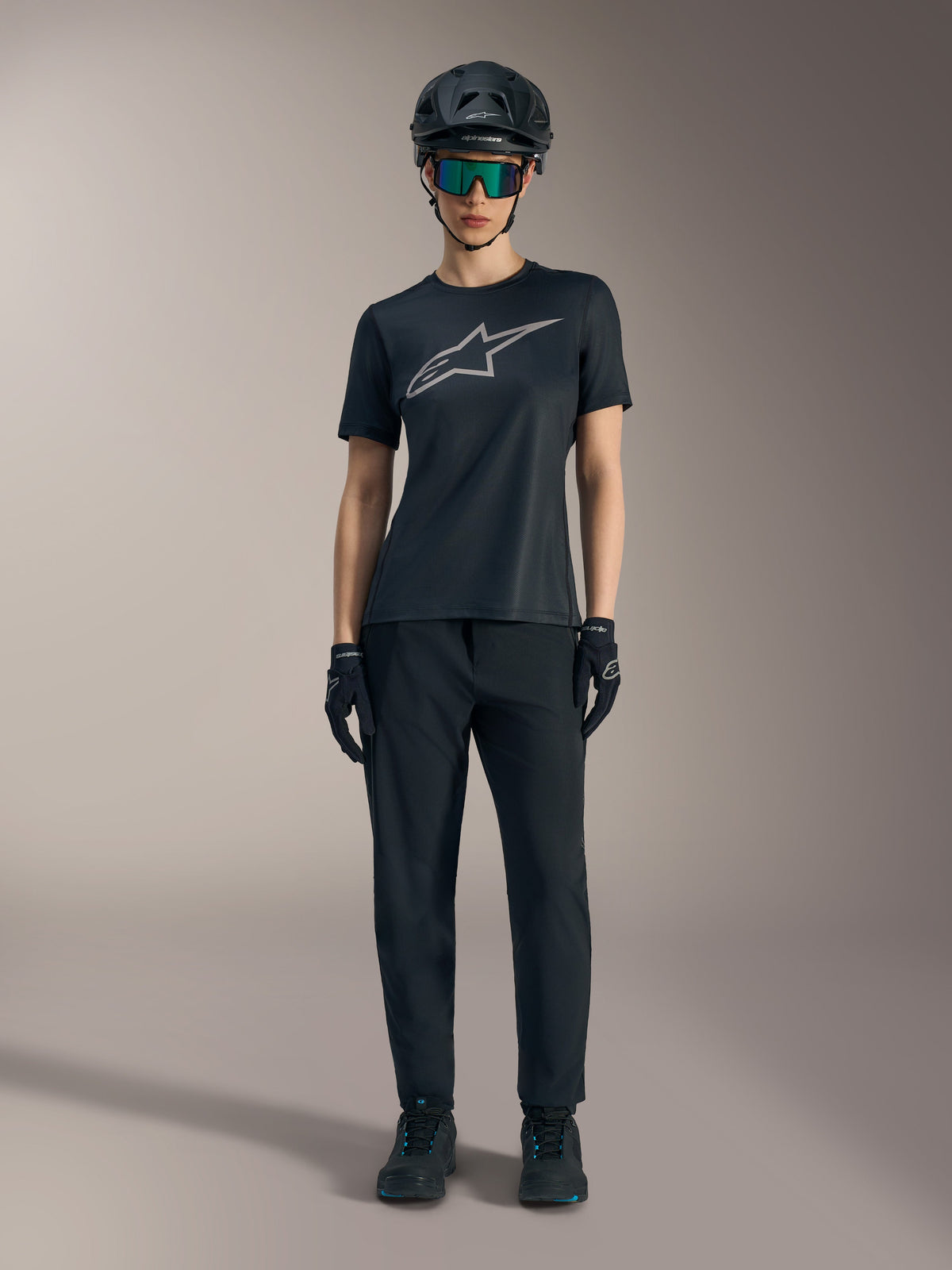 Maillot femme Stella A-Dura Ride noir à manches courtes, logo argenté, pantalon de VTT et casque tout-terrain.