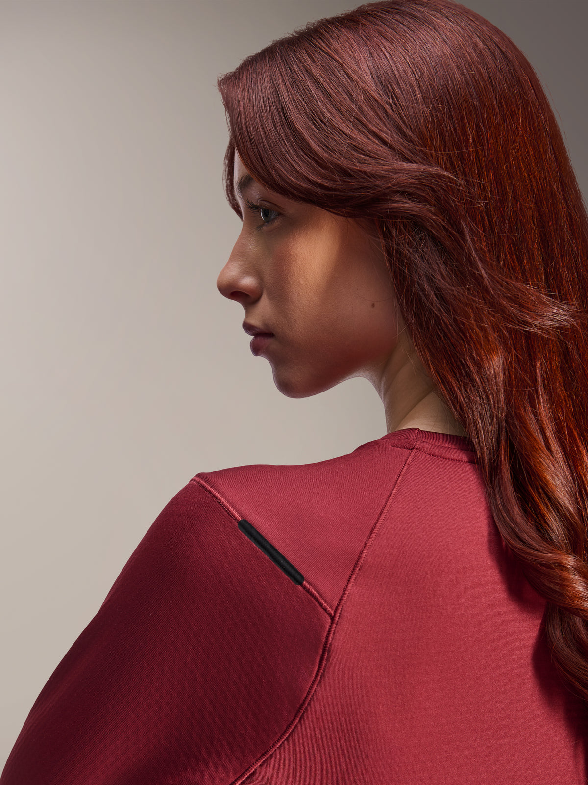 Femme portant le maillot Alpinestars Stella A-Dura Thermal, maillot de VTT à manches longues bordeaux, vue rapprochée de profil, mettant l'accent sur les détails des coutures d'épaule et la texture de la matière, équipement de cyclisme lifestyle