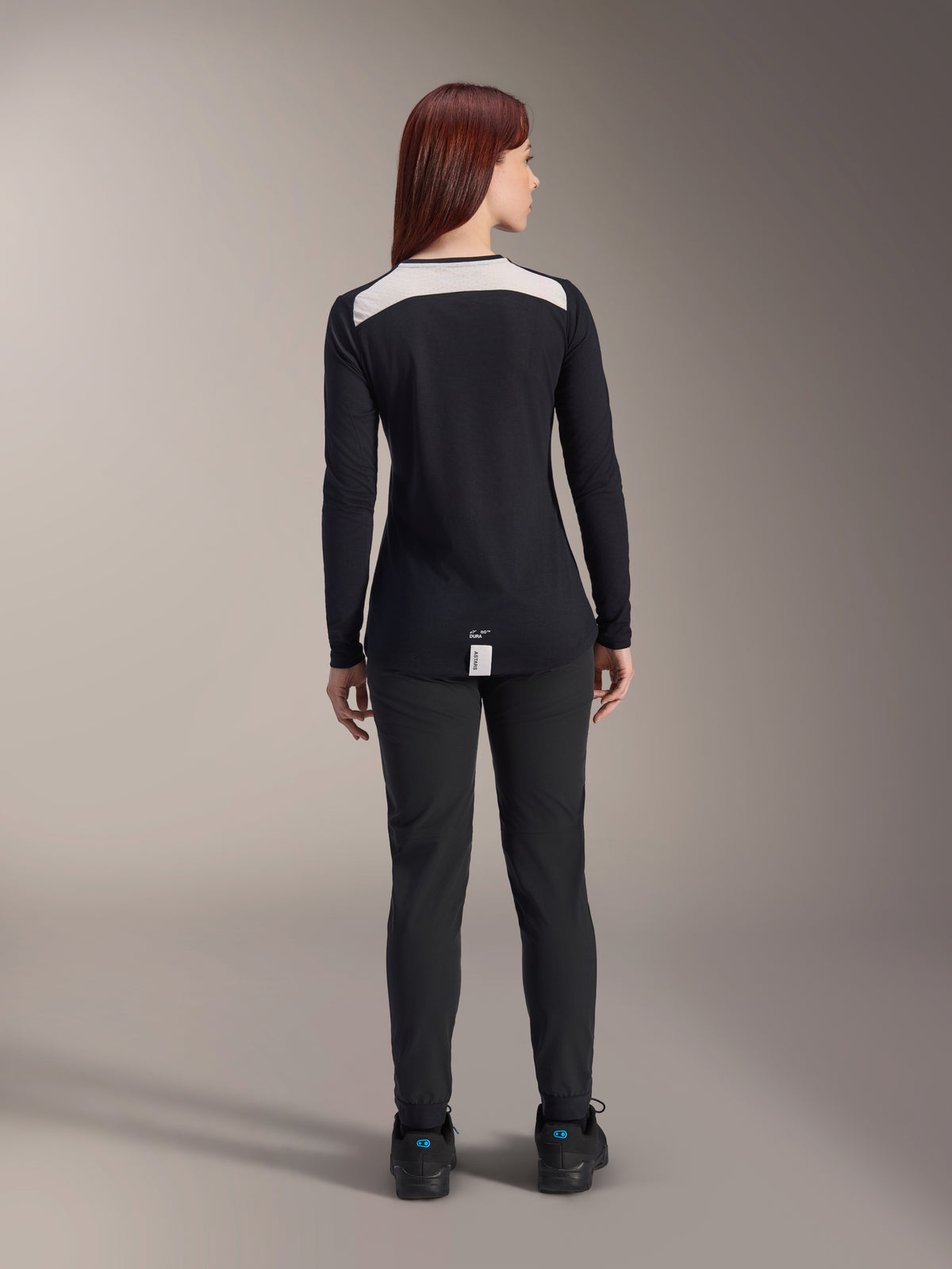 Maillot à manches longues Alpinestars Stella A-Dura Dri Astar, maillot de VTT noir pour femme, vue arrière présentant un panneau de ventilation en maille blanche sur les épaules, associé à un pantalon de cyclisme noir, équipement technique de tout-terrain