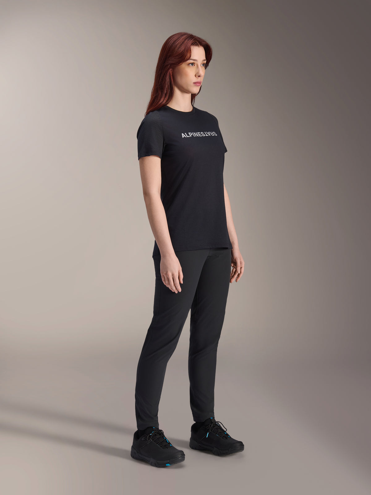 Maillot Alpinestars Stella A-Dura Dri Switch, maillot de cyclisme à manches courtes, noir avec logo Alpinestars blanc, porté par un mannequin femme avec un pantalon et des chaussures noirs assortis, équipement polyvalent pour le VTT.